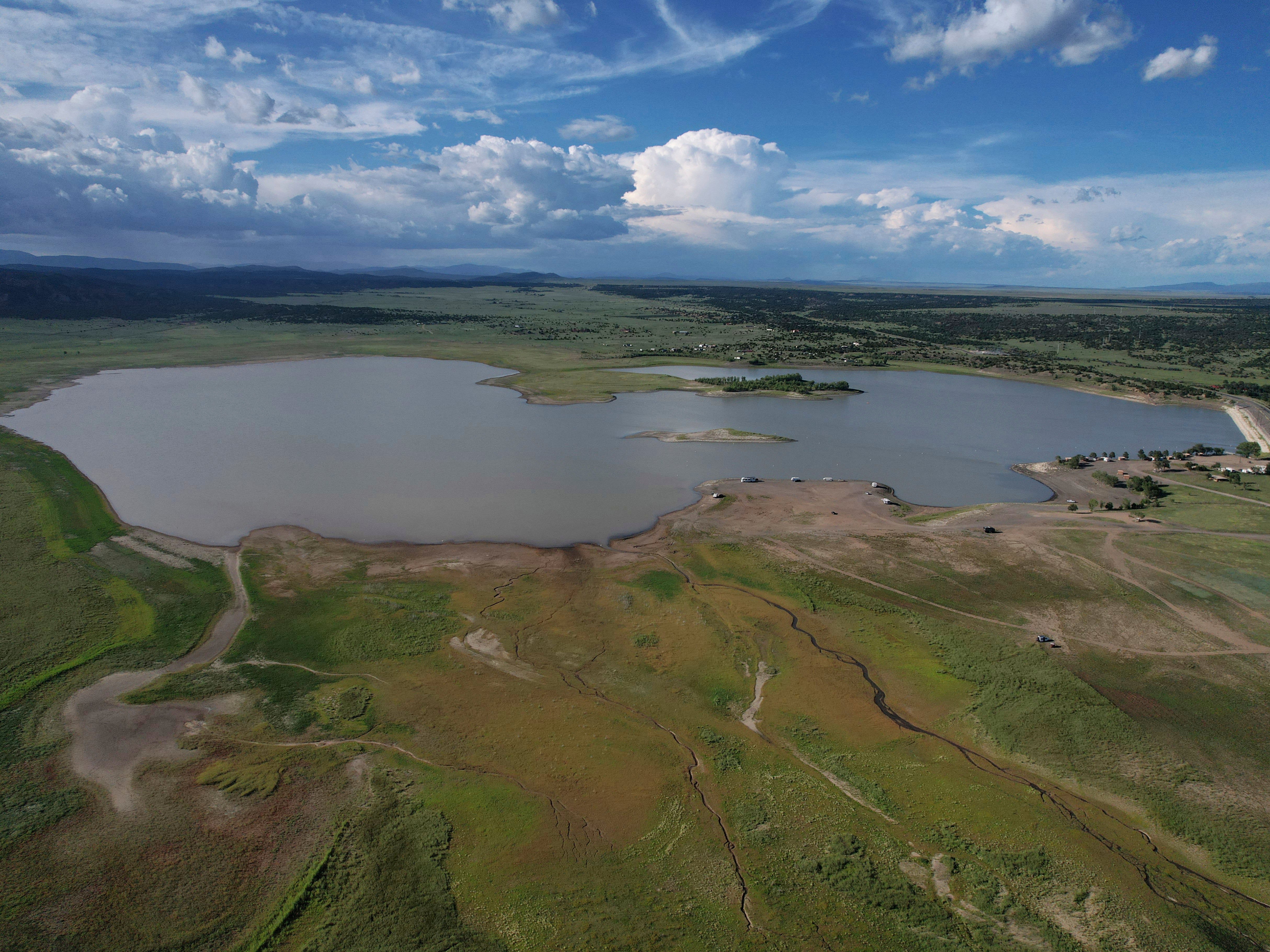 Storrie Lake is seen Tuesday, Aug. 9, 2022, near Las Vegas, N.M. The clock is ticking as the city's water supply rapidly depletes following a fire and floods. A temporary treatment system is being installed here that should bring this water, also affected from the floods, up to drinking water standards. (AP Photo/Brittany Peterson)