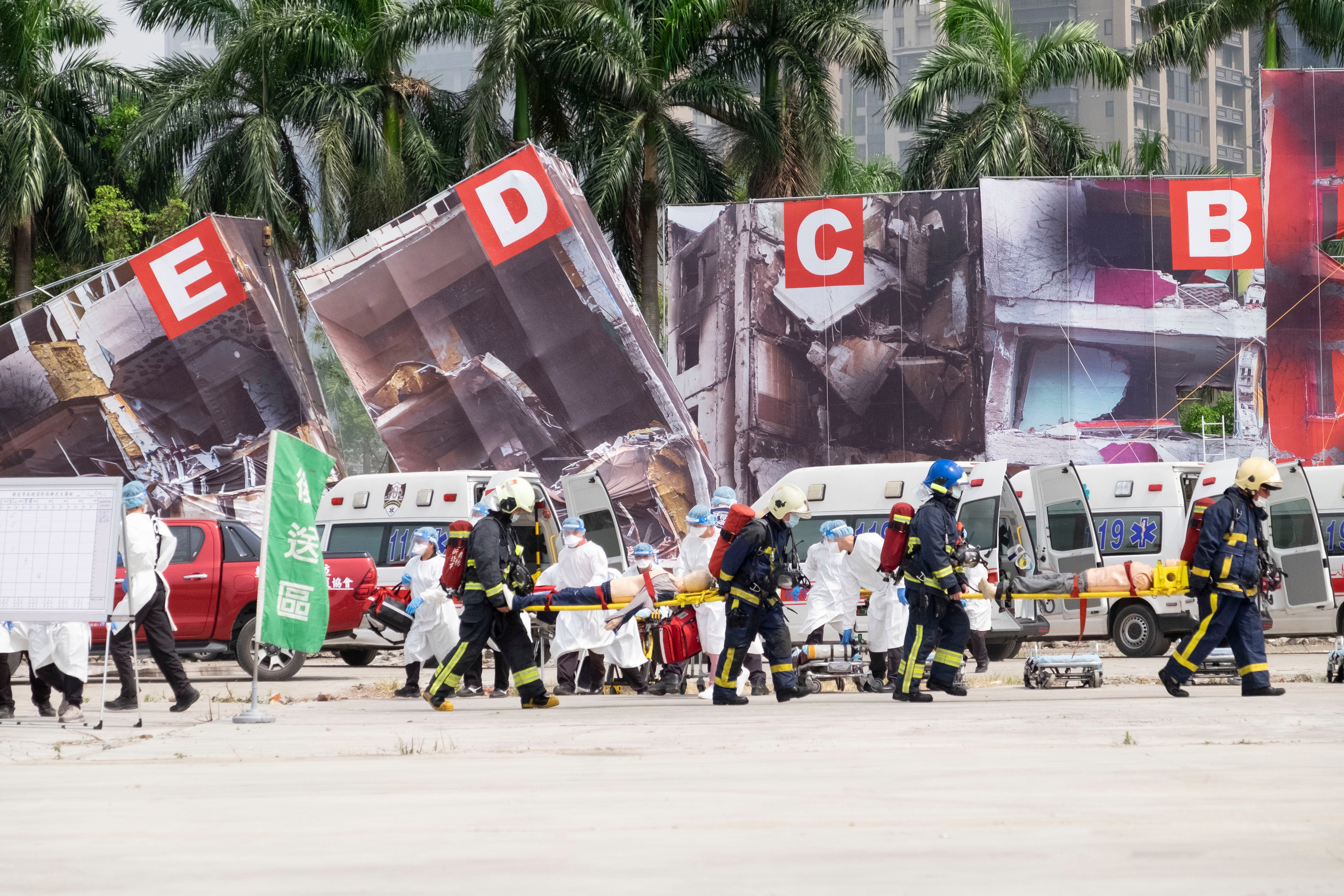 Firefighters and medical personnel carry dummy victims on stretchers during a drill in New Taipei