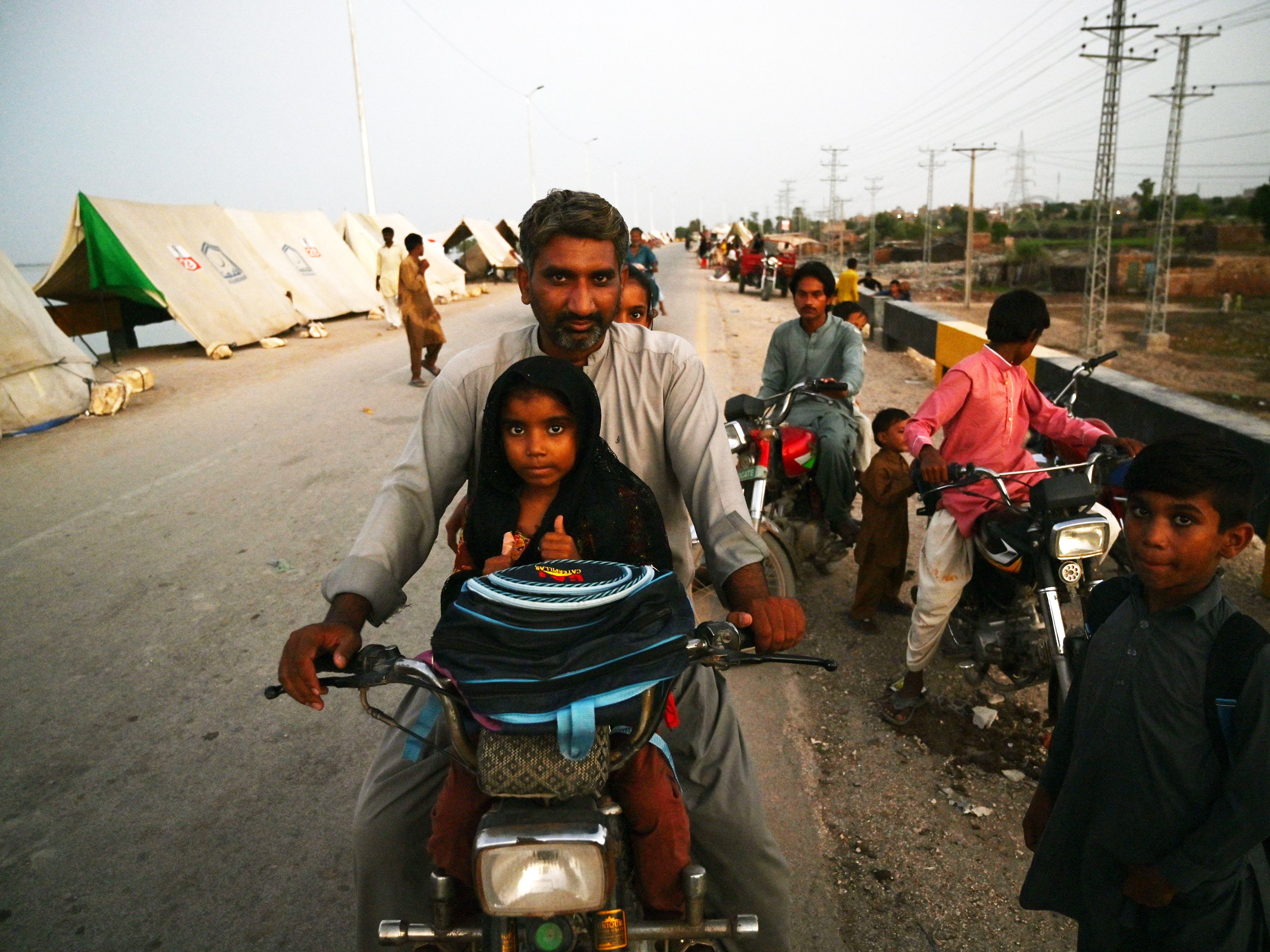 Displaced people gather at a makeshift camp by flood waters after heavy monsoon rains in Sukkur, Sindh province