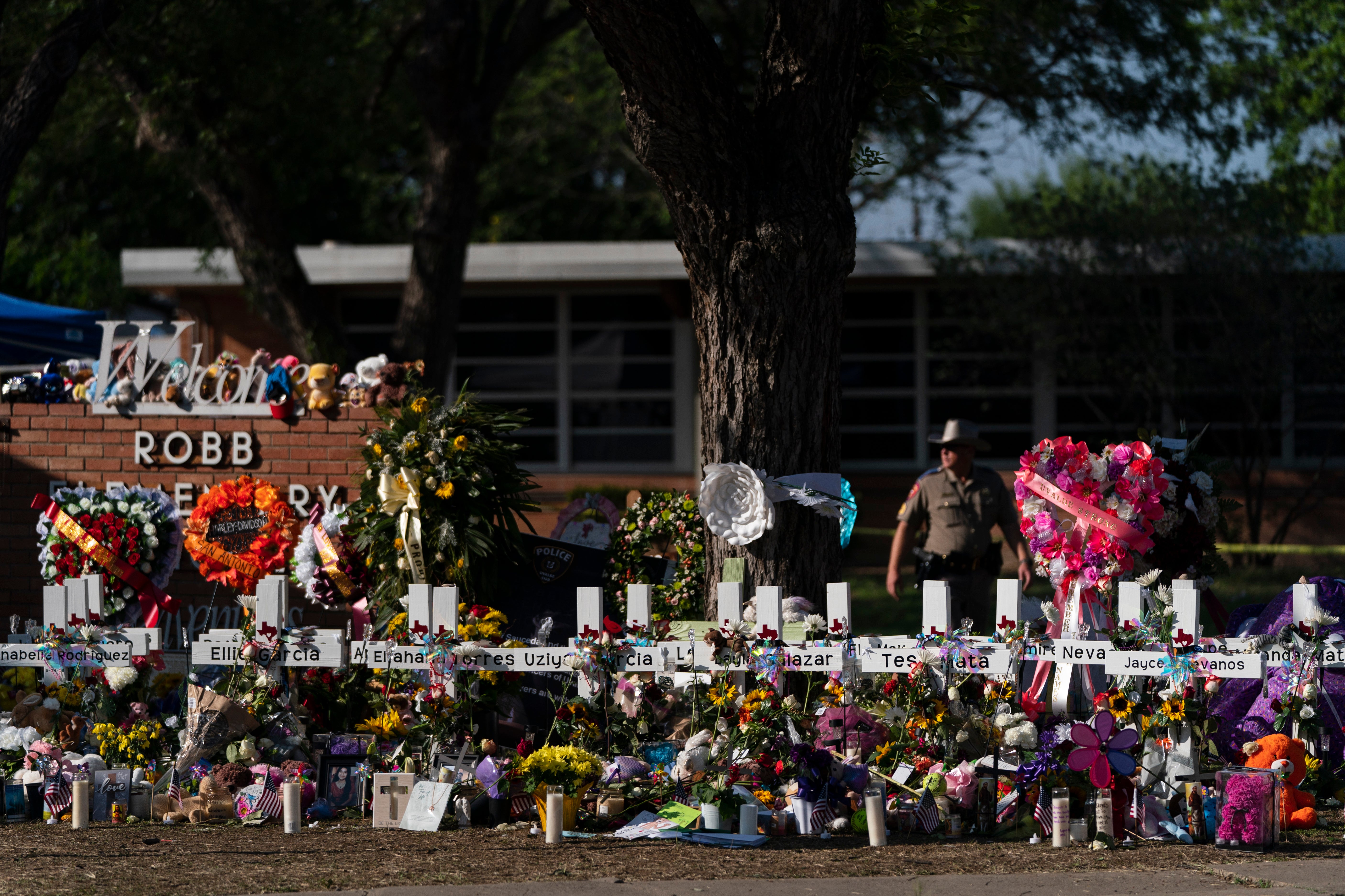 Flowers and candles are placed around crosses at a memorial outside Robb Elementary School for the victims