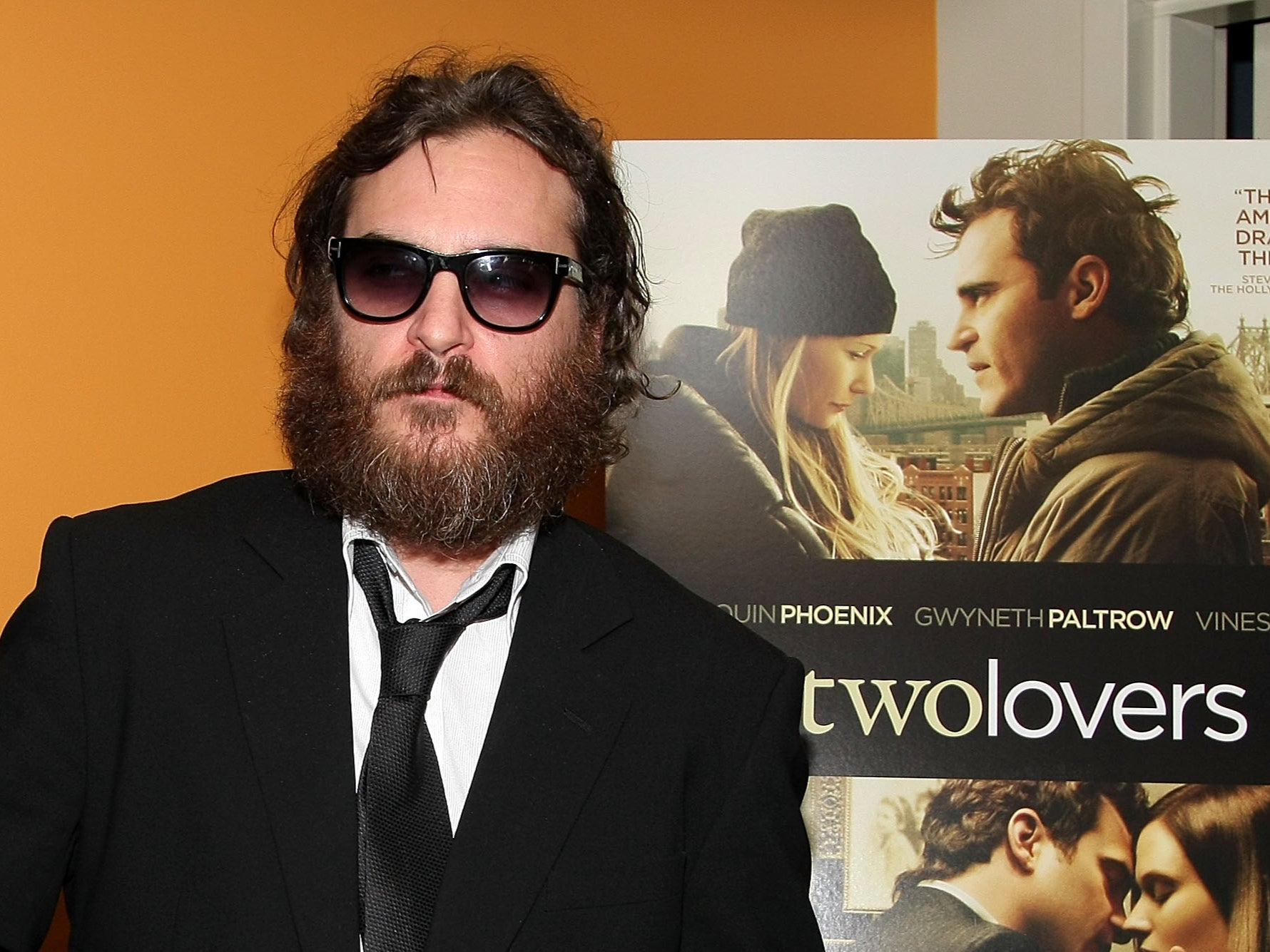 Joaquin Phoenix poses dispassionately in front of a poster for his film ‘Two Lovers’ in 2009