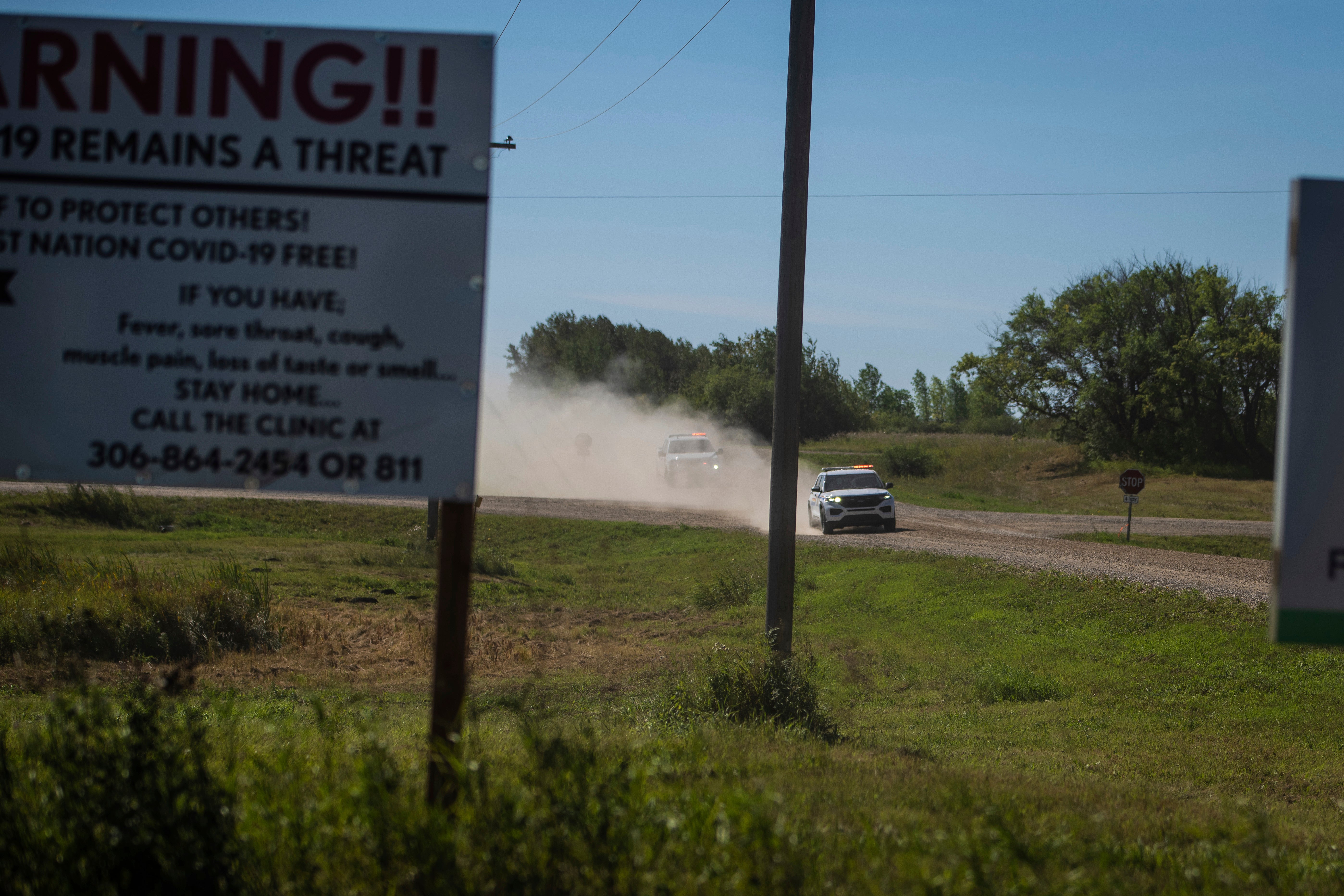 Canadian law enforcement personnel rush to surround a home on the James Smith Cree First Nation reservation in Saskatchewan, Canada, Tuesday, Sept. 6, 2022, as they search for a suspect in a series of stabbings