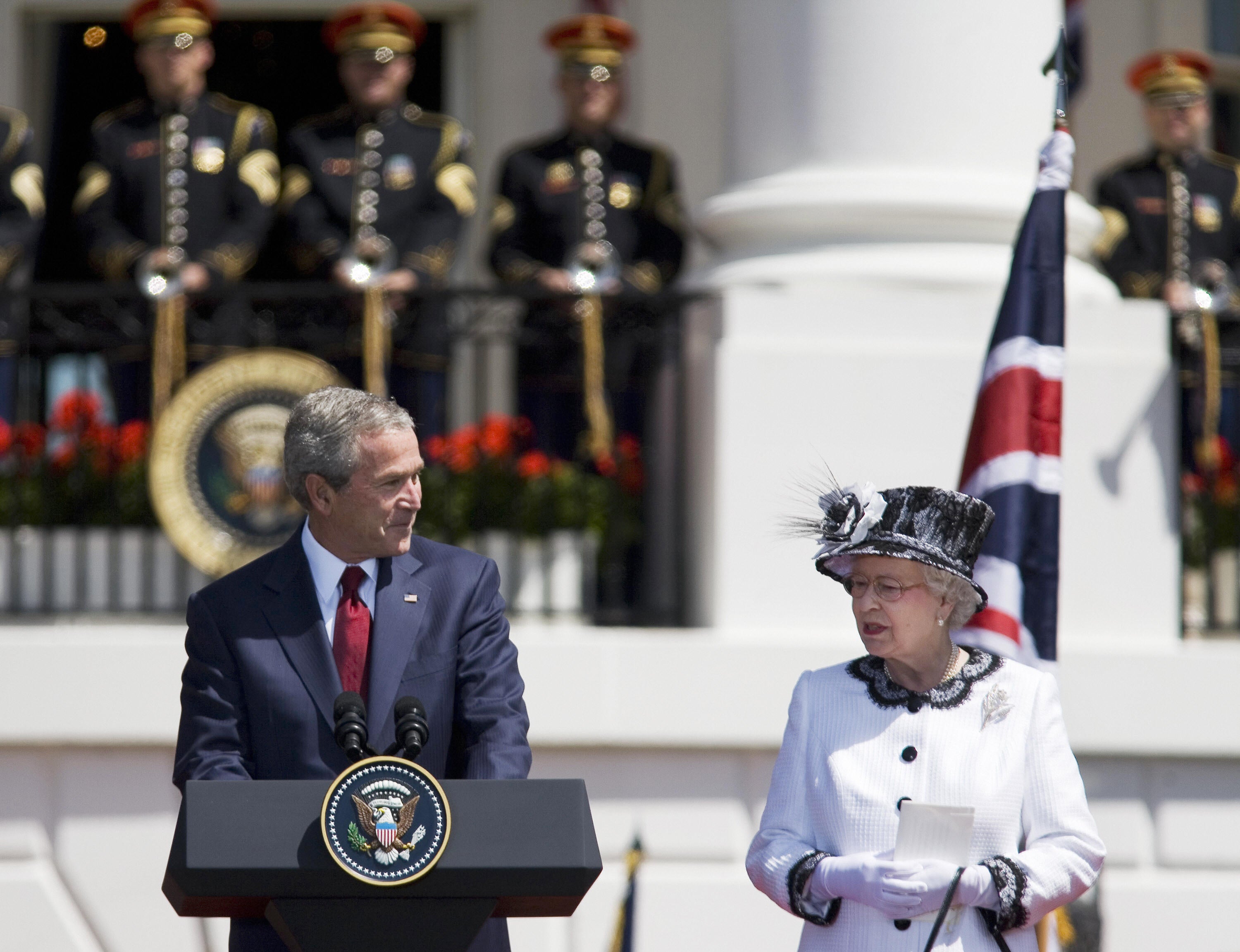 President George W Bush looks over at Queen Elizabeth II while giving remarks at the White House