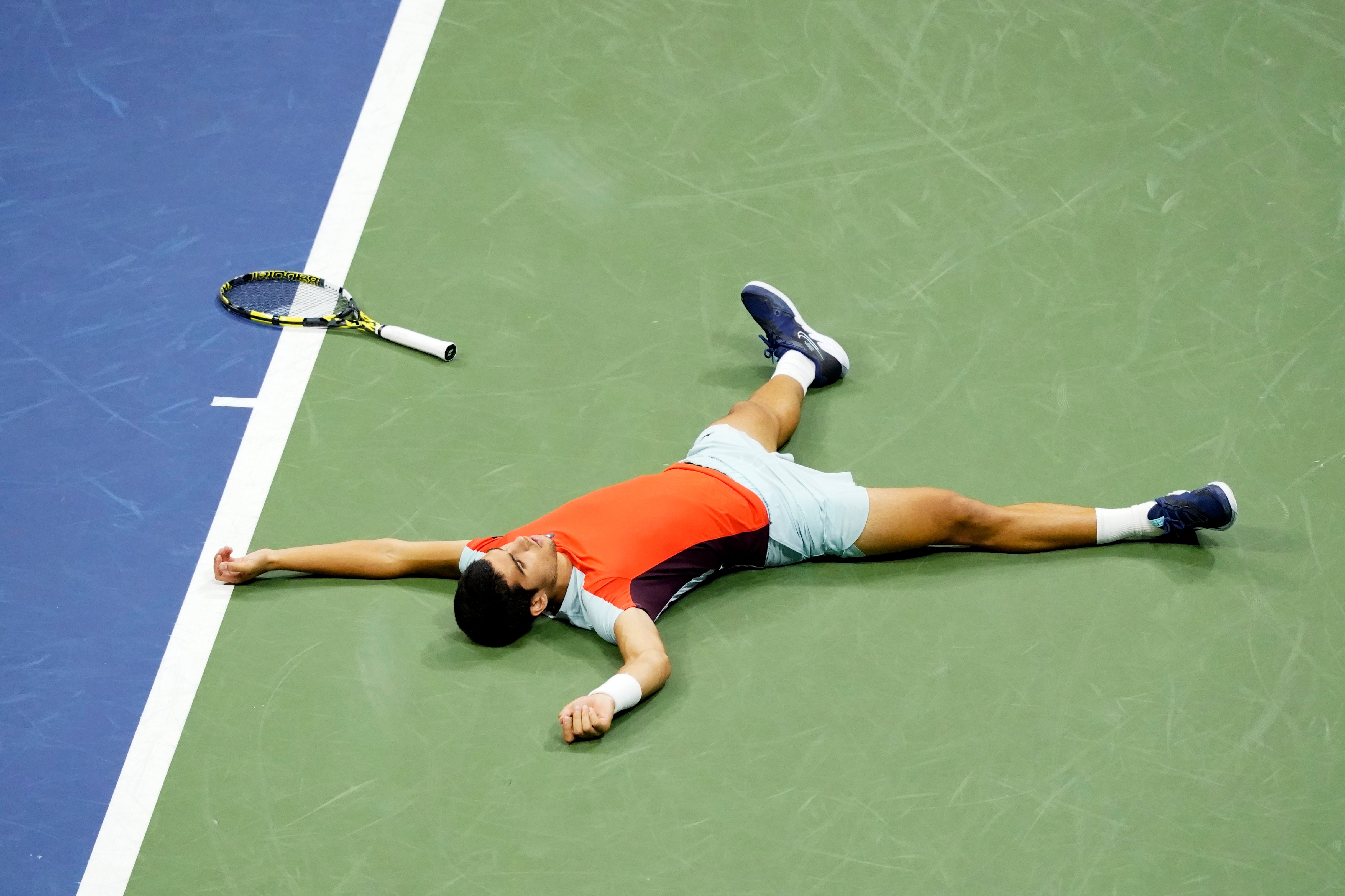 Carlos Alcaraz lies on the court after reaching the US Open final (Mary Altaffer/AP)