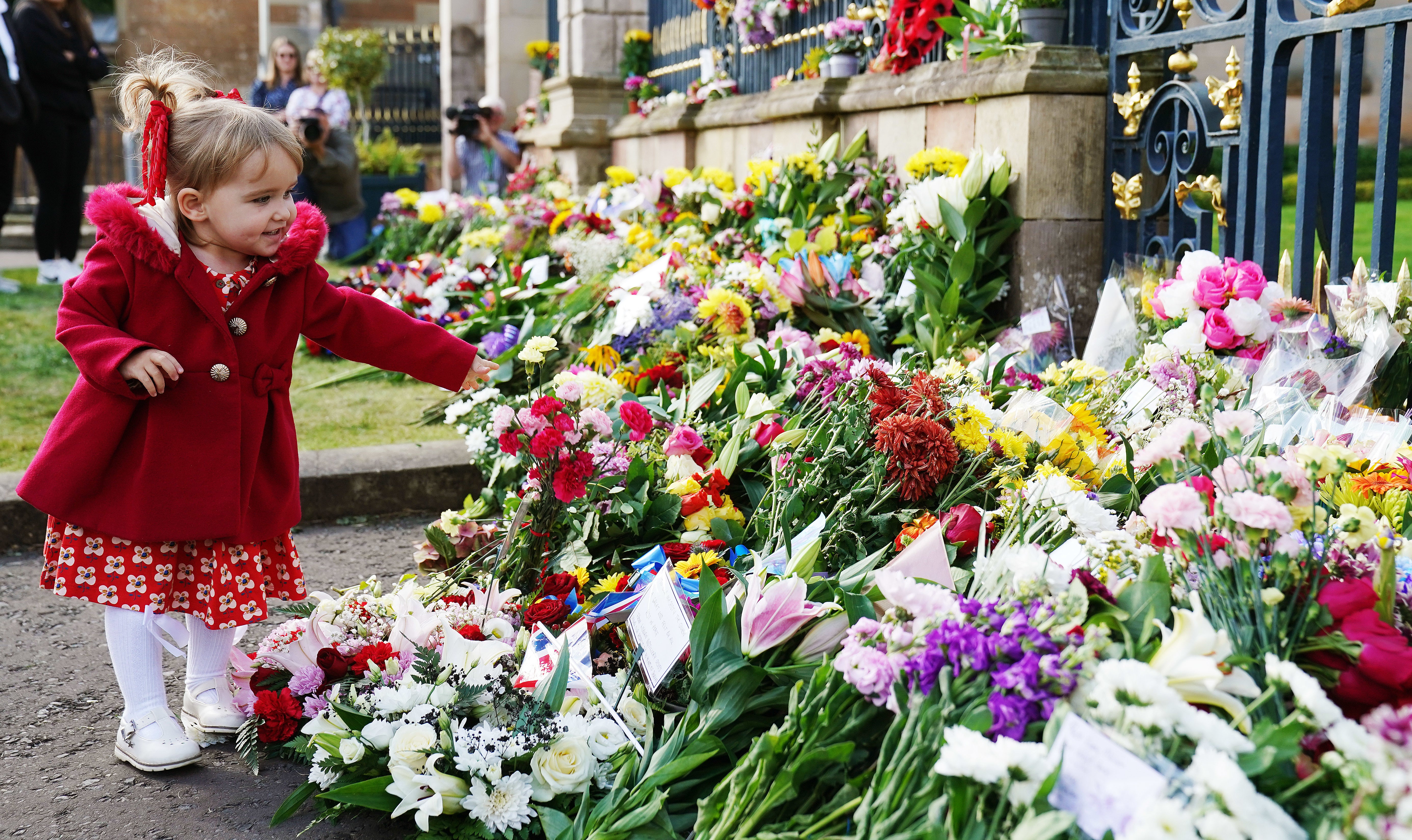 Abigail Glen (2), from Lisburn, lays flowers at the gates of Hillsborough Castle, Co. Down, following the death of Queen Elizabeth II on Thursday (Brian Lawless/PA)