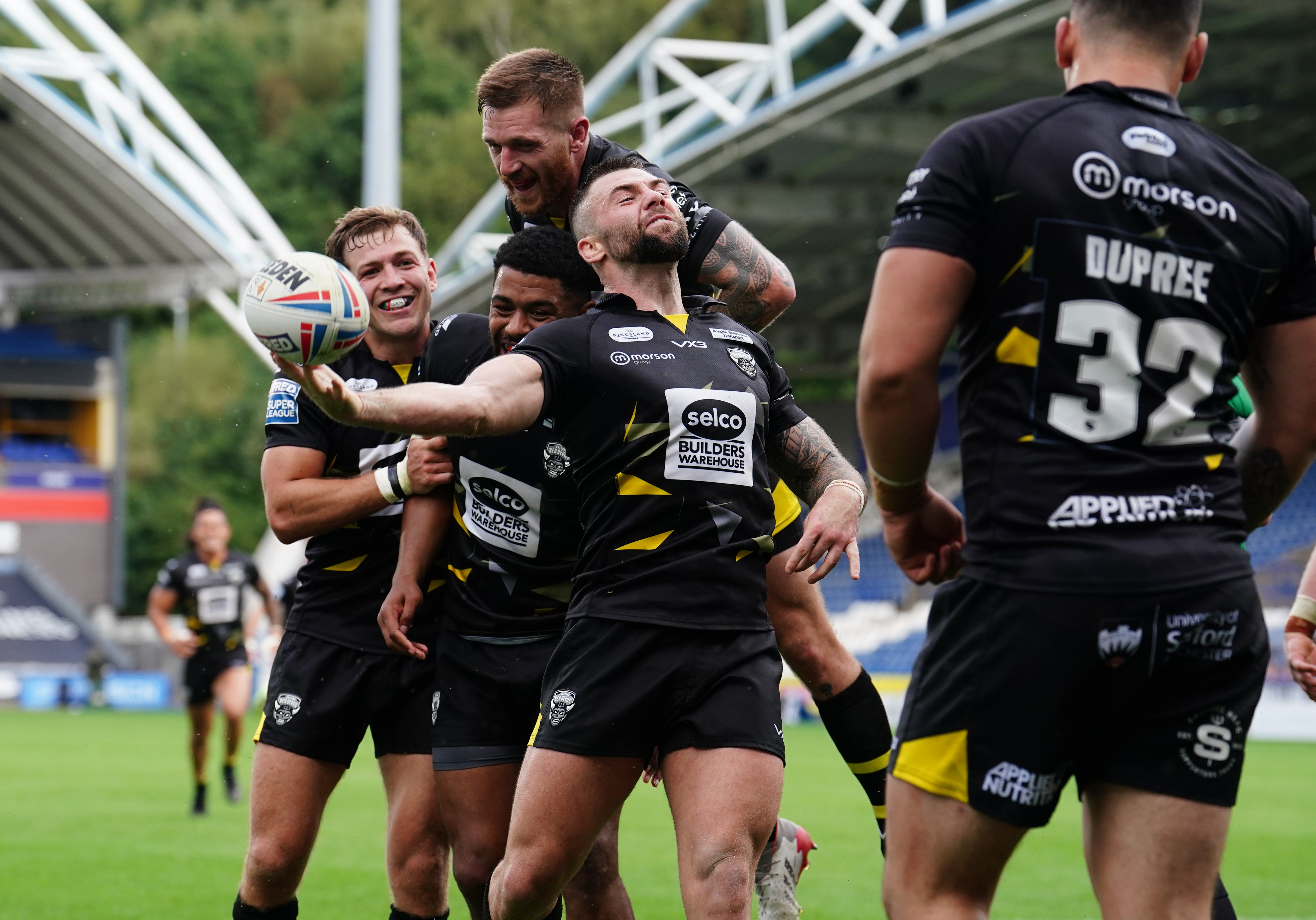 Andy Ackers, centre, and Salford celebrate their final try against Huddersfield (Martin Rickett/PA)