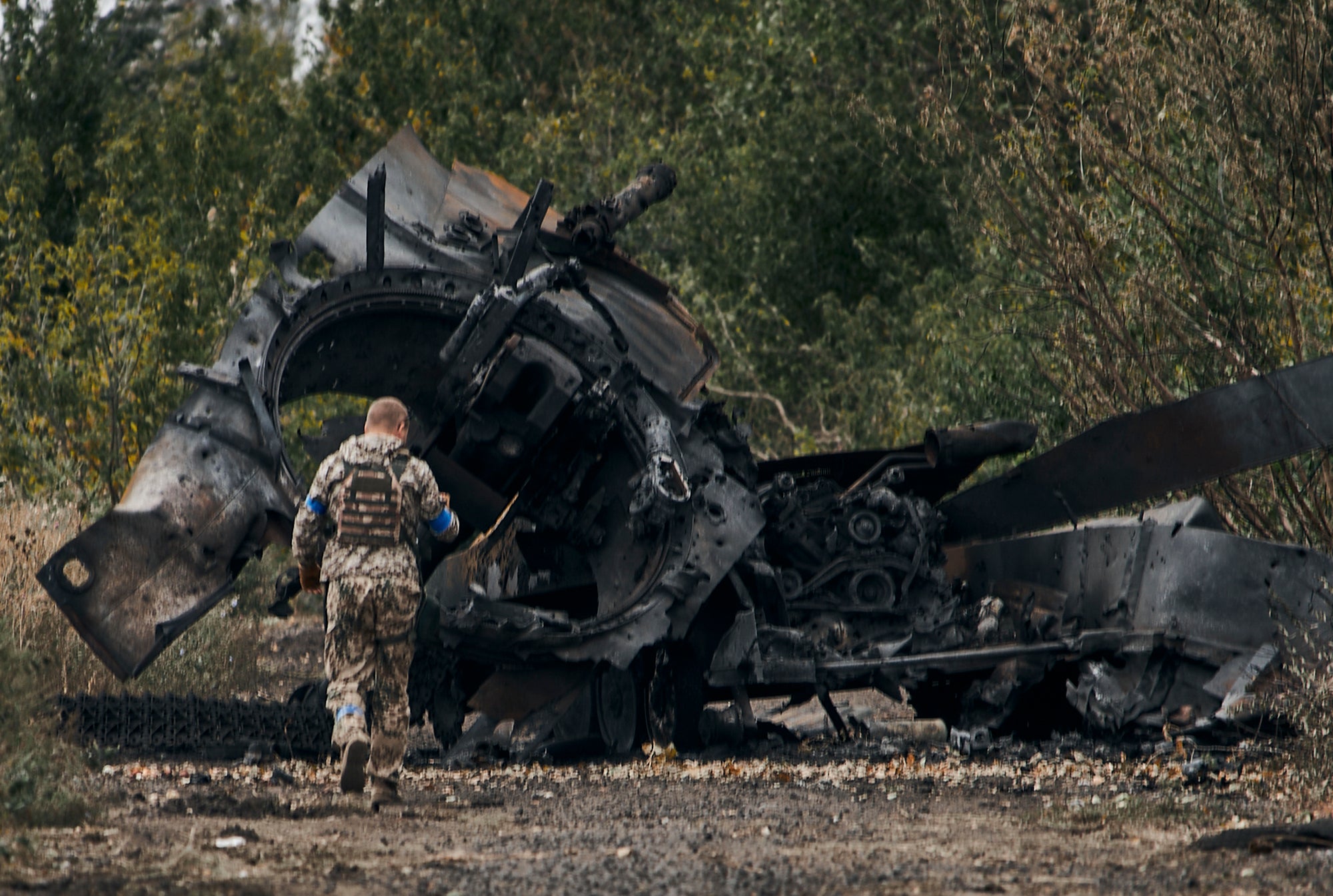 A Ukrainian soldier approaches a Russian tank damaged in a battle near Balakleya in the Kharkiv region