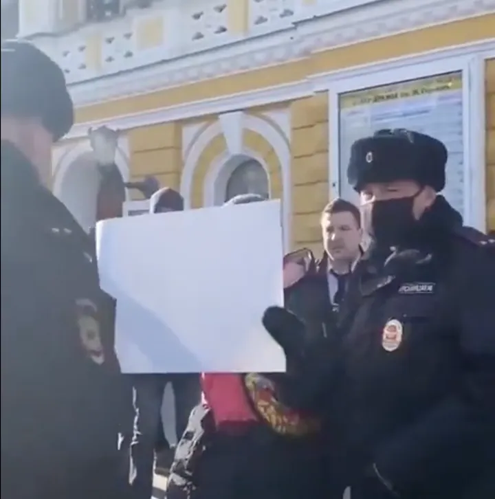 Russian police dragged the woman away for holding up a blank sign