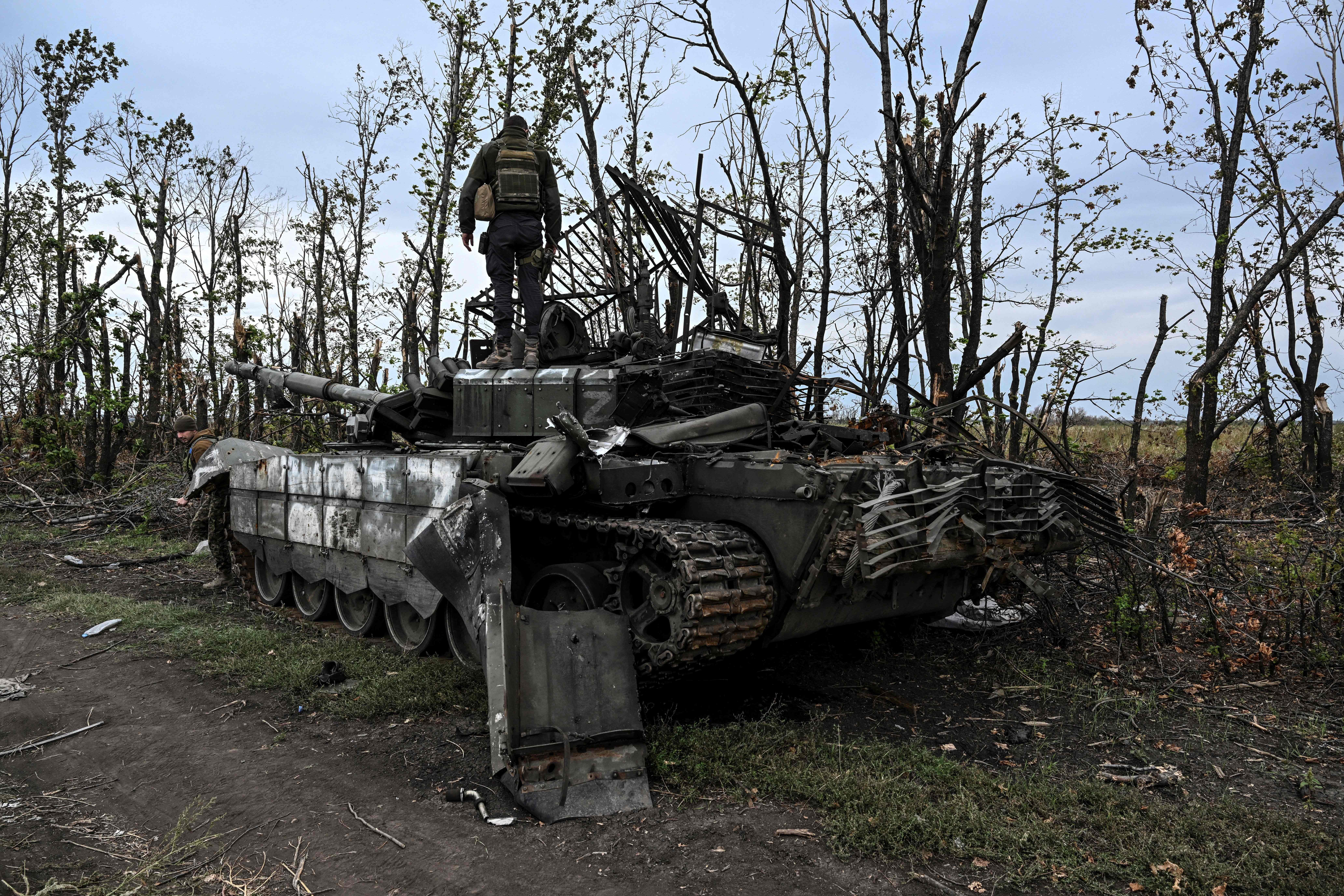 This photograph taken on 11 September 2022, shows a Ukranian soldier standing atop an abandoned Russian tank near a village on the outskirts of Izyum, Kharkiv Region, eastern Ukraine, amid the Russian invasion of Ukraine