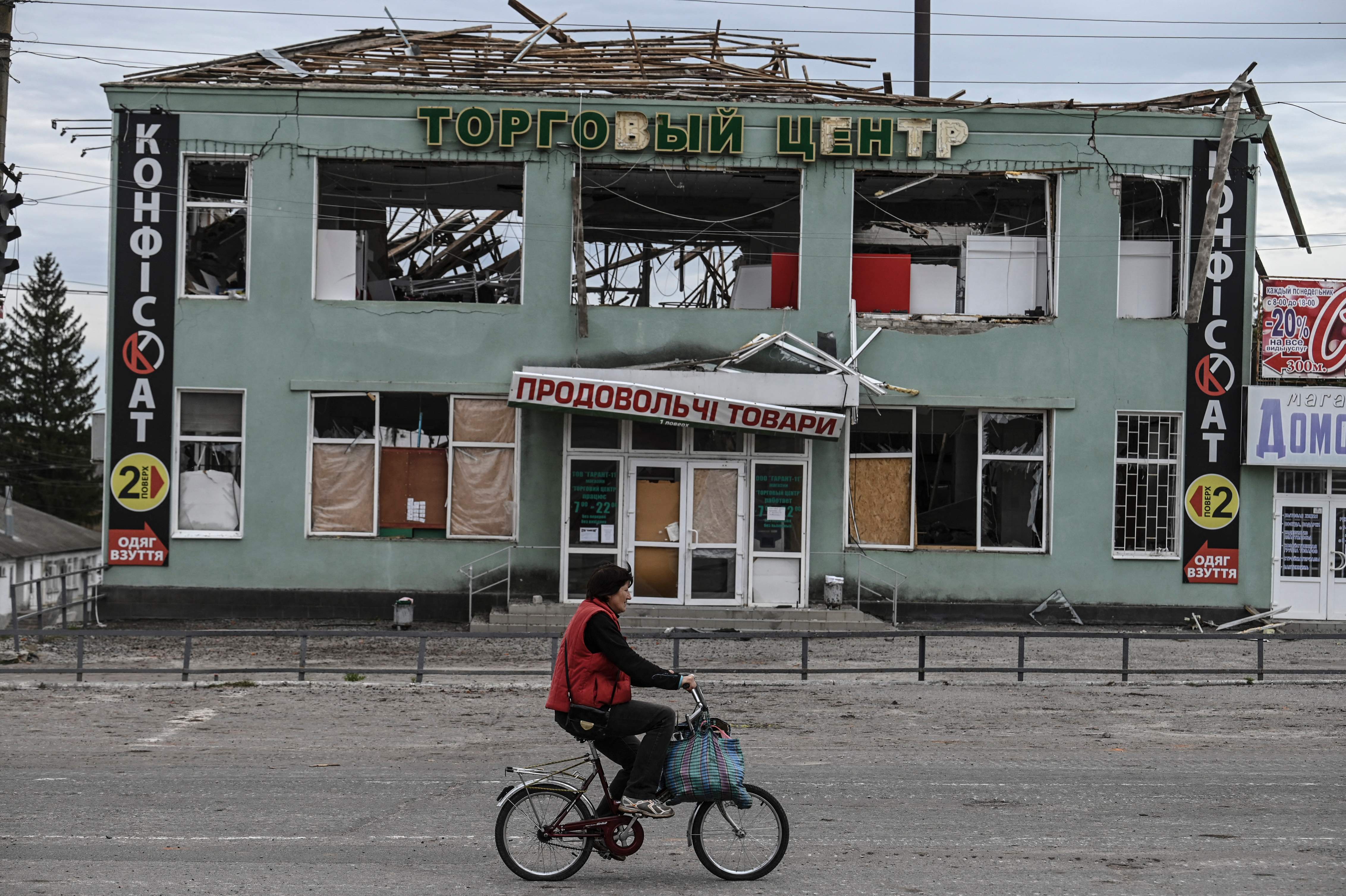 Free wheeling: A local woman passes a destroyed building in Balakliya after Ukrainian forces liberated the town