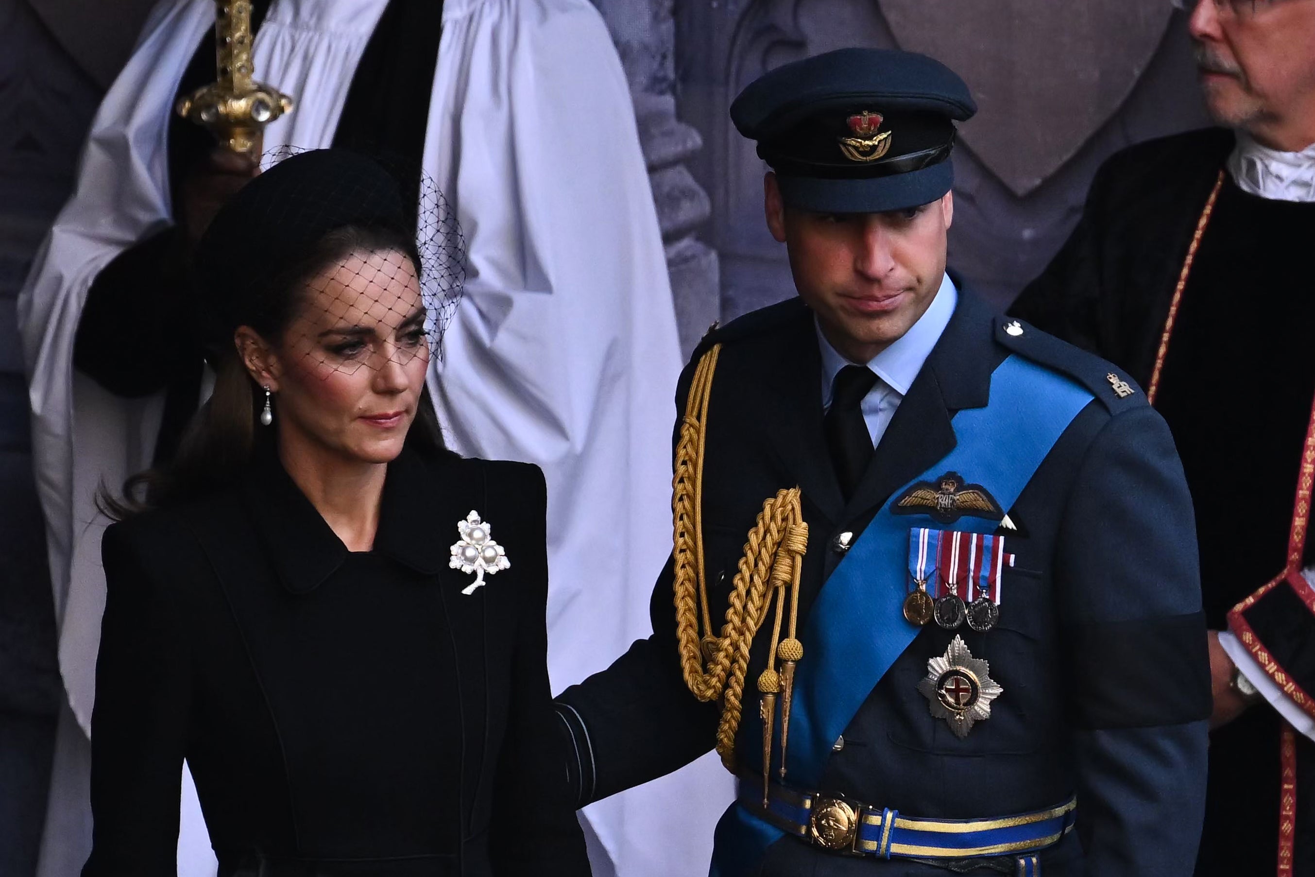 William places his hand on Kate’s back as they depart Westminster Hall service