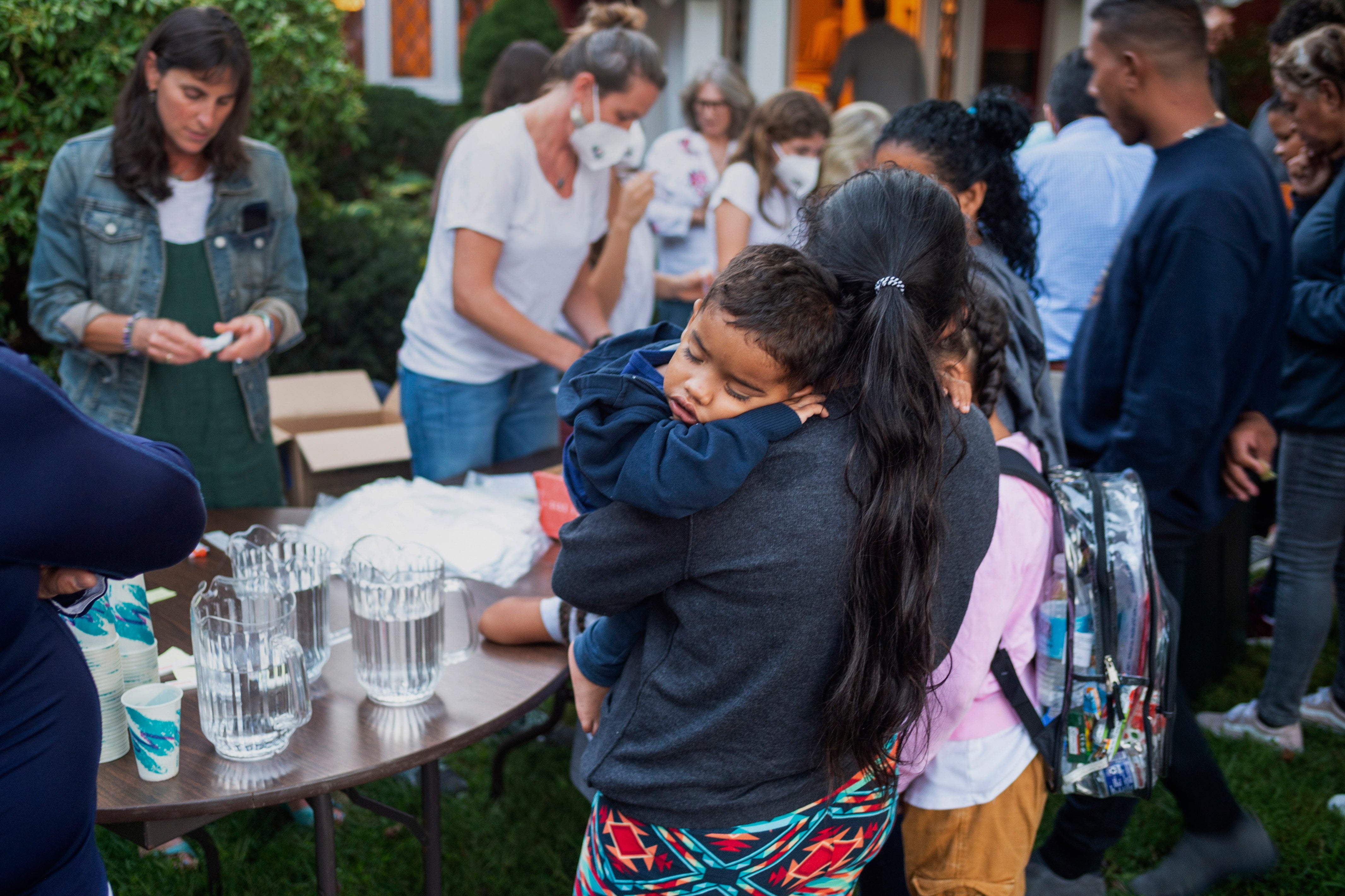 A woman, who is part of a group of immigrants that had just arrived, holds a child as they are fed outside St Andrews Episcopal Church