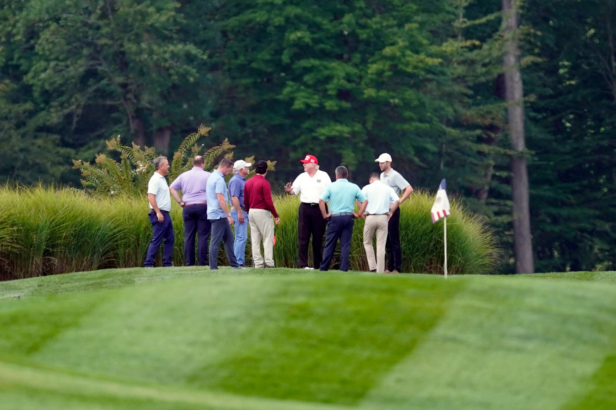 Donald Trump stands on his golf course with others at Trump National Golf Club on Monday