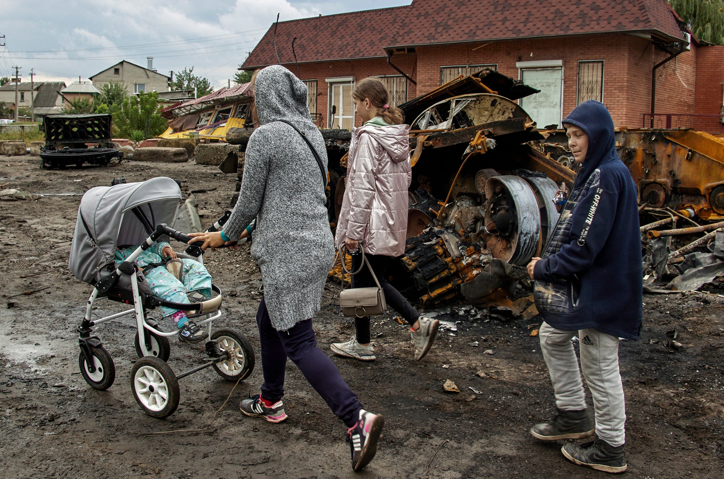 Residents walk past the remains of a tank in Izyum after the city was liberated from Russian occupation