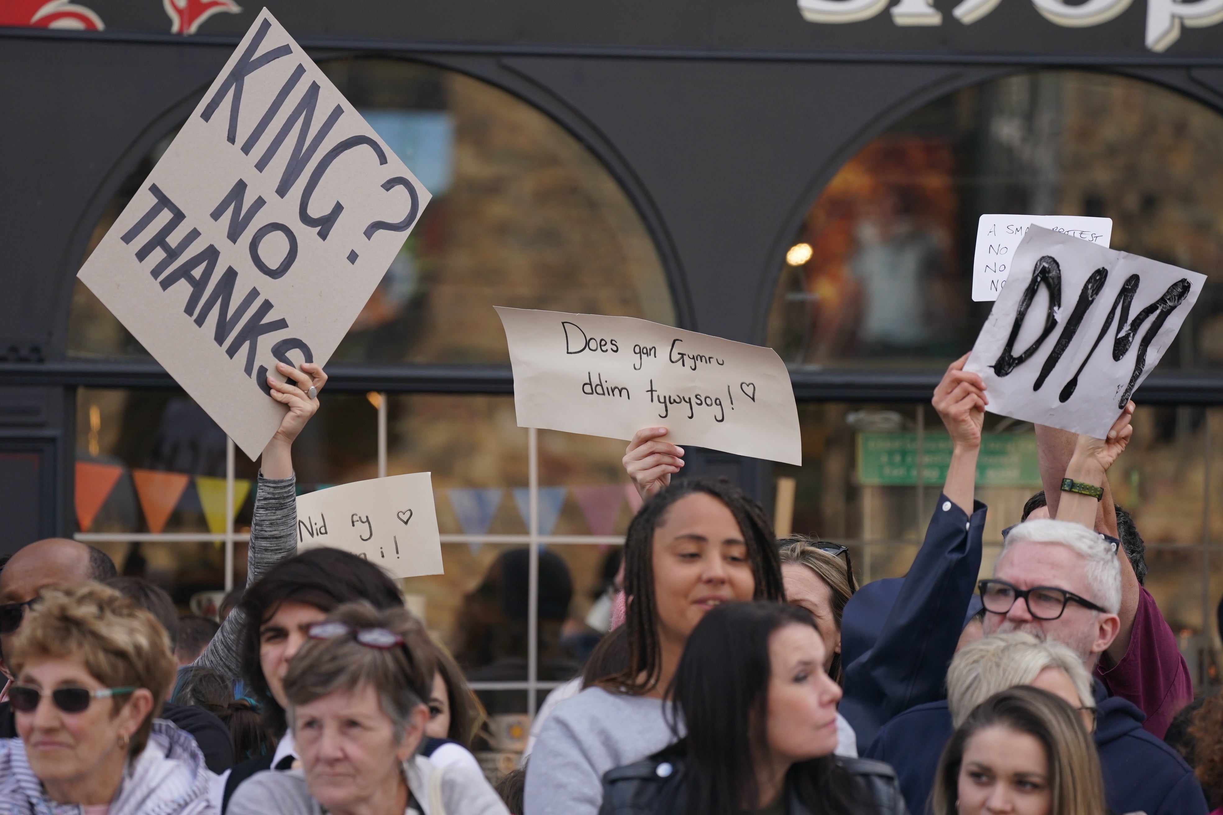 A small protest is seen as King Charles III and the Queen Consort arrive at Cardiff Castle in Wales (Jacob King/PA)