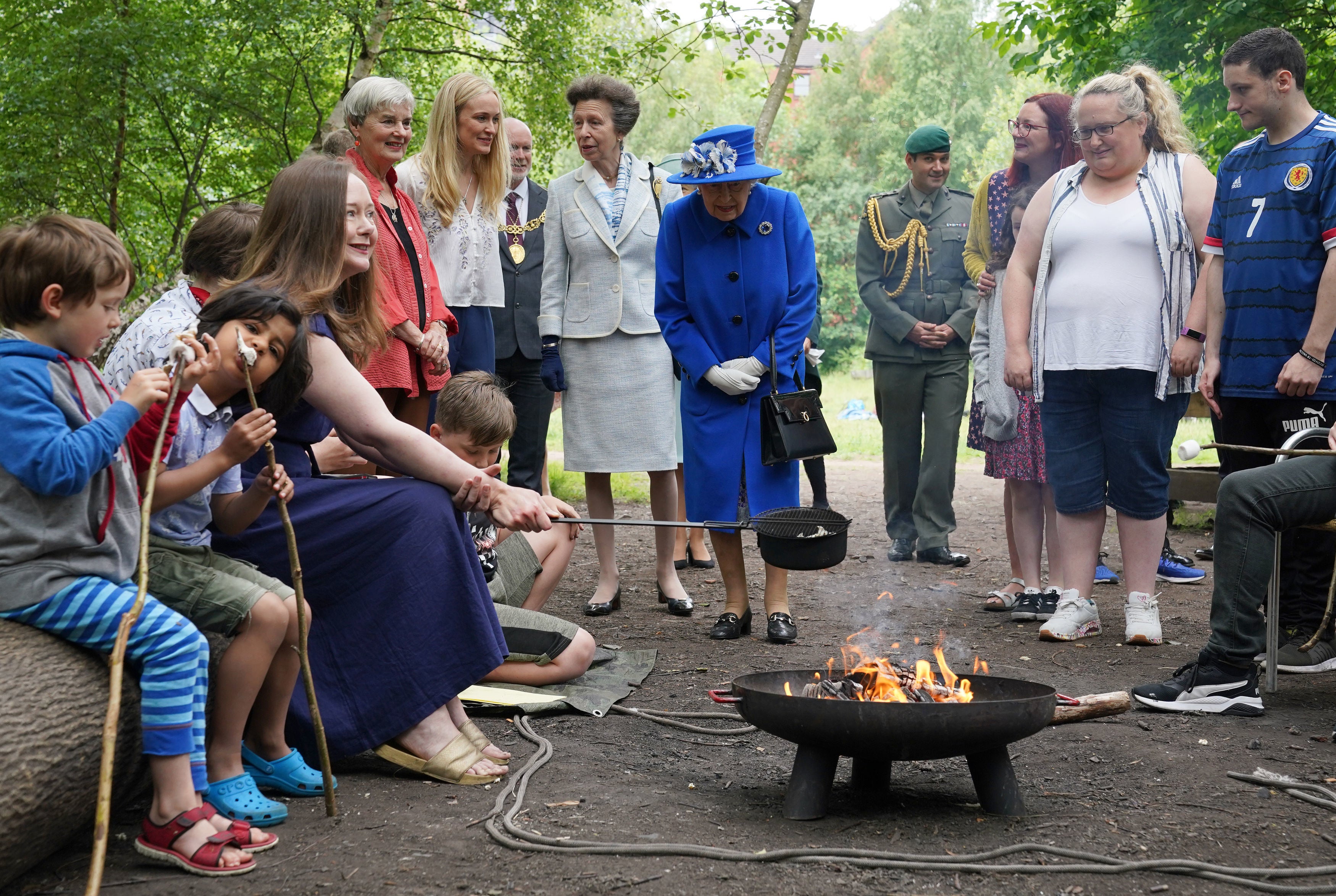 Queen Elizabeth II and Princess Anne, Princess Royal view marshmallows being toasted as they visit the Children's Wood Project, a community project in Glasgow as part of her traditional trip to Scotland for Holyrood Week on June 30, 2021 in Glasgow, Scotland.