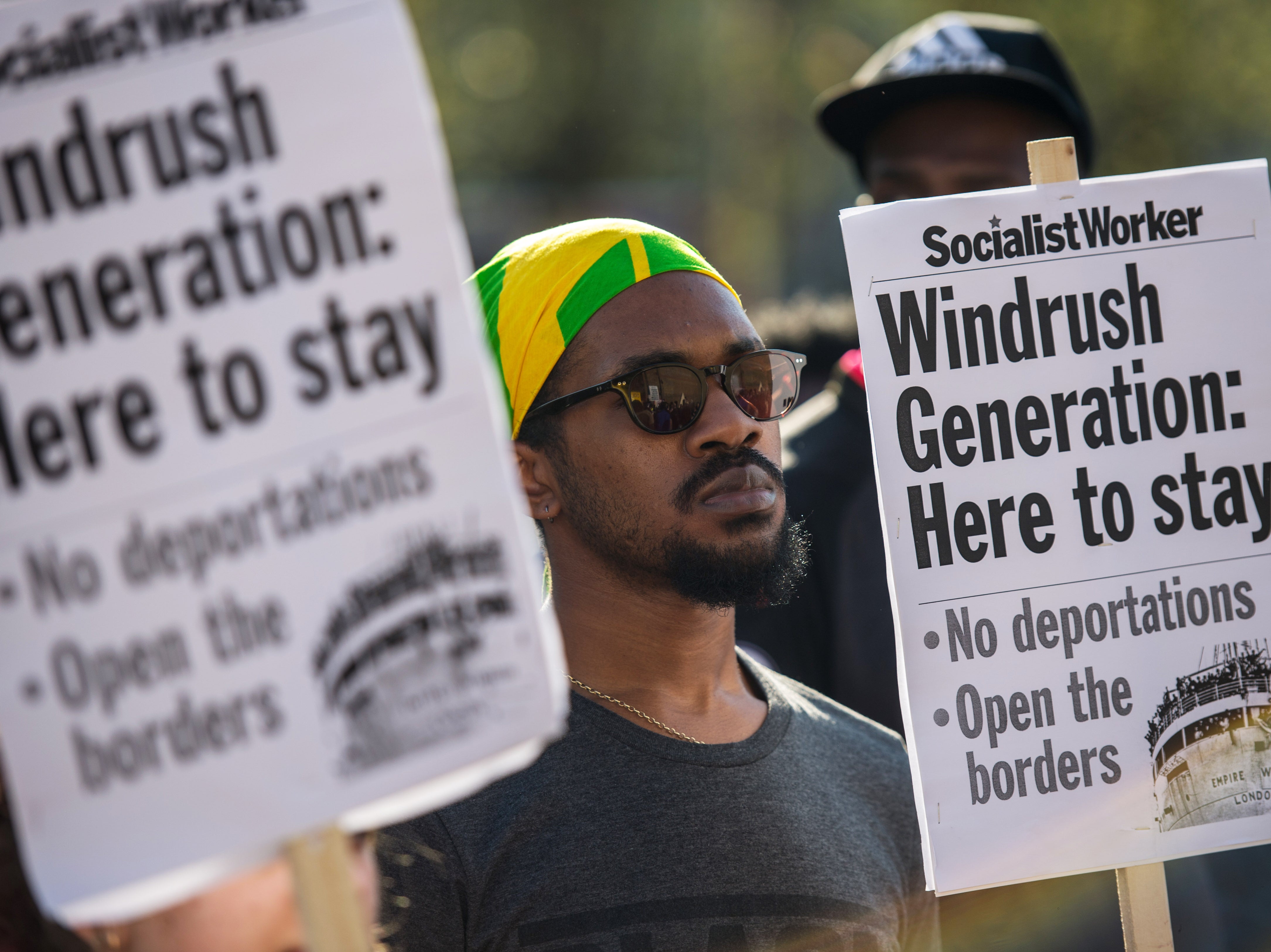 Demonstrators hold placards during a protest in support of the Windrush generation in Windrush Square