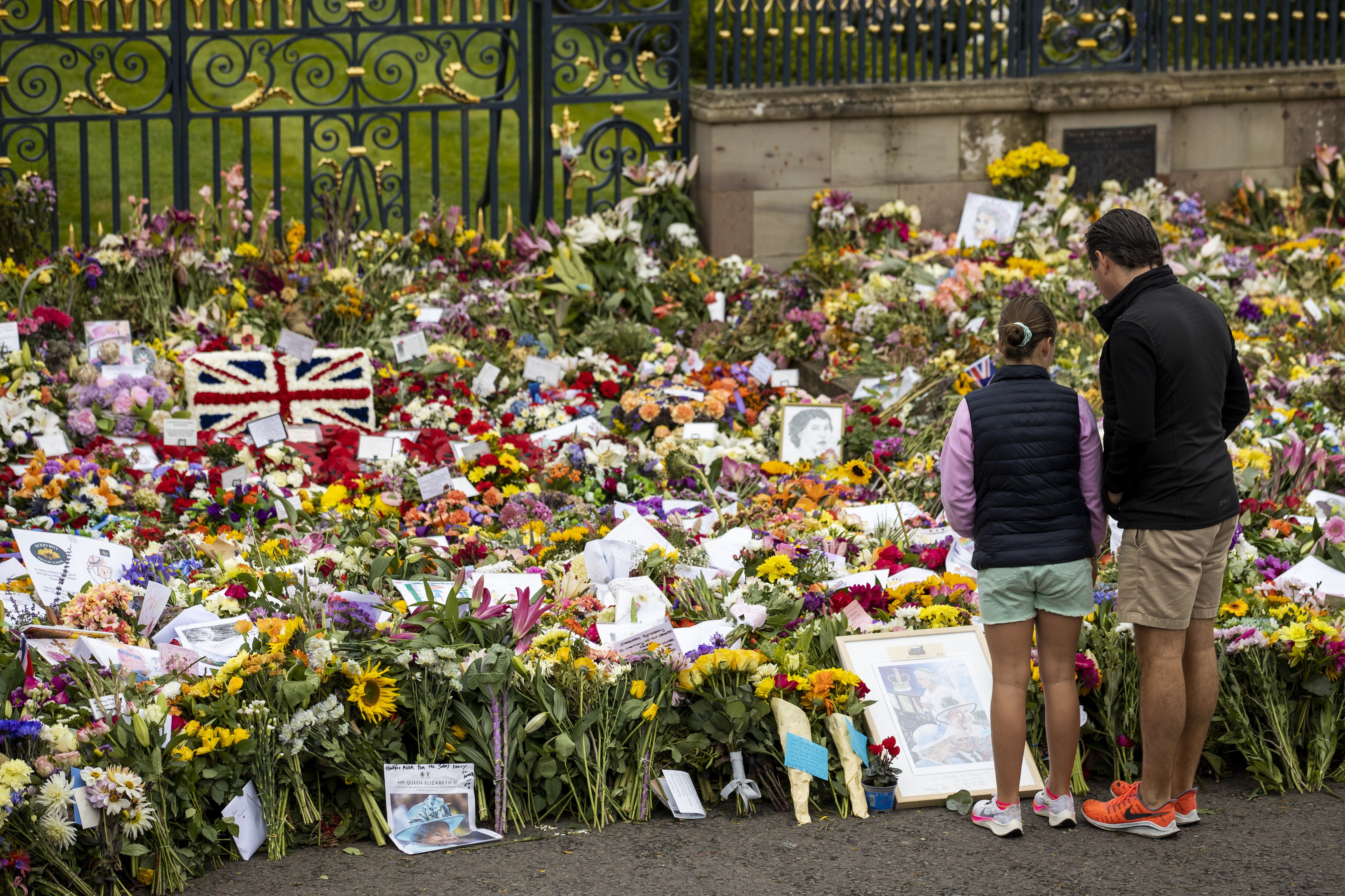 Members of the public look at flowers and wreaths left in remembrance of Queen Elizabeth II at Hillsborough Castle (Liam McBurney/PA)