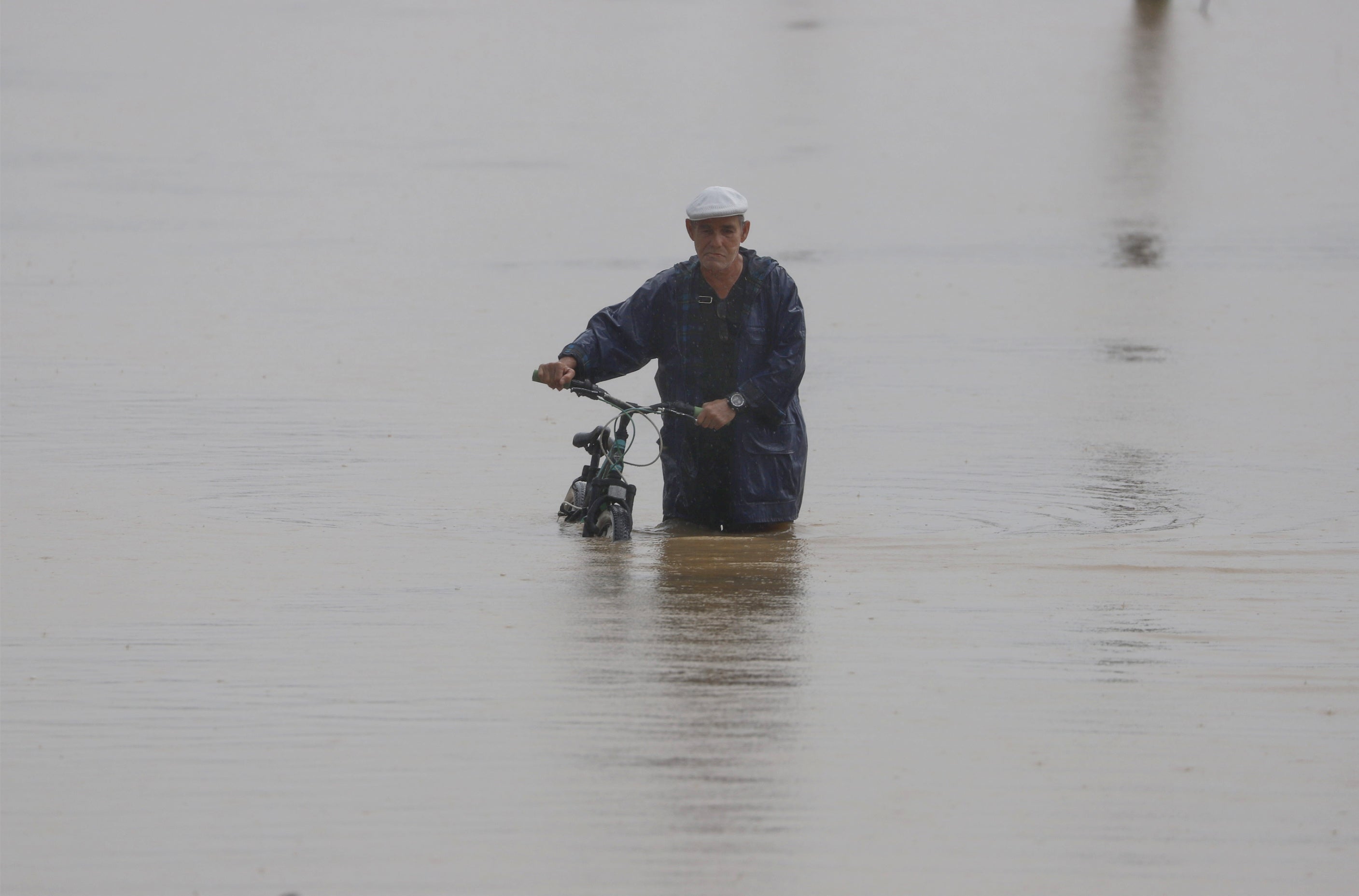 A man with a bicycle walks in a flooded street after the passage of hurricane Fiona, in Toa Baja, Puerto Rico