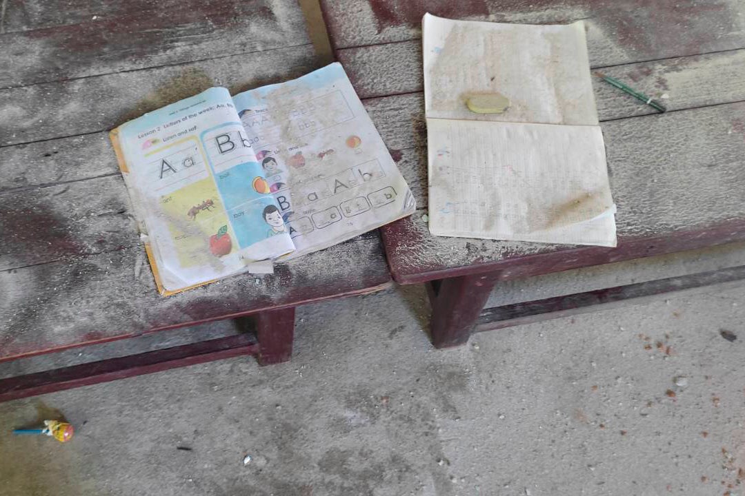 An alphabet book and a notebook lie on top of an elevated wooden floorboard of a middle school in Let Yet Kone village