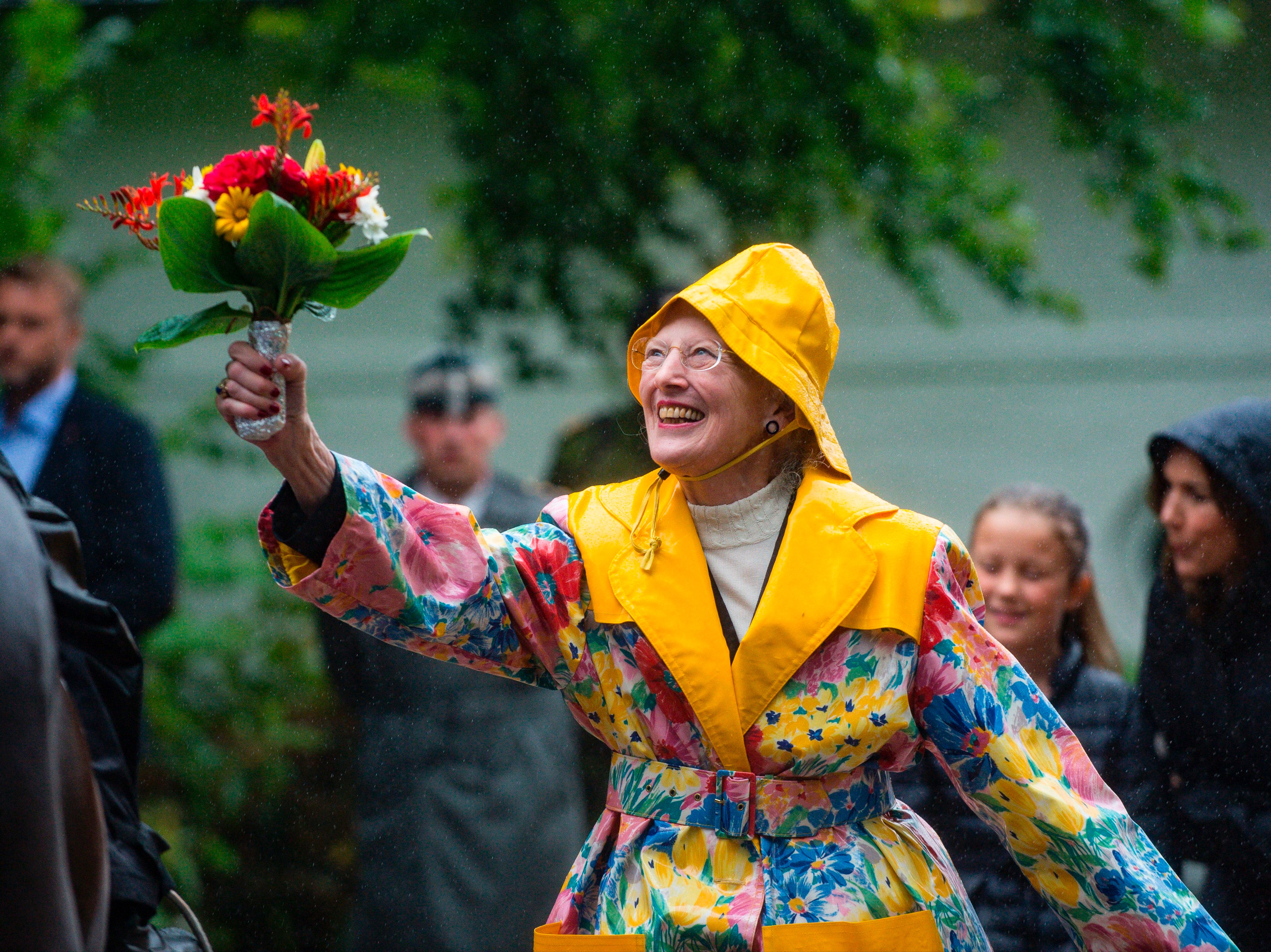 Queen Margrethe accepts flowers from the parade at Graasten Castle wearing her notorious raincoat