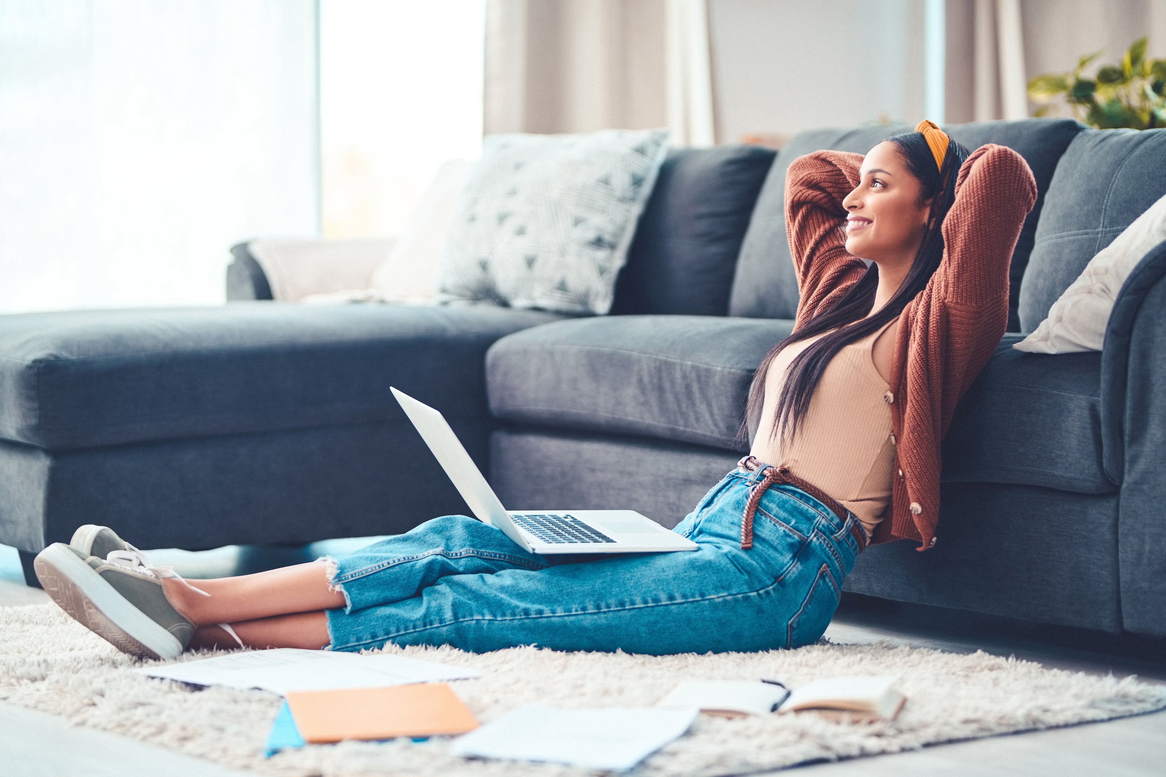 Shot of a young woman relaxing while working in the living room at home