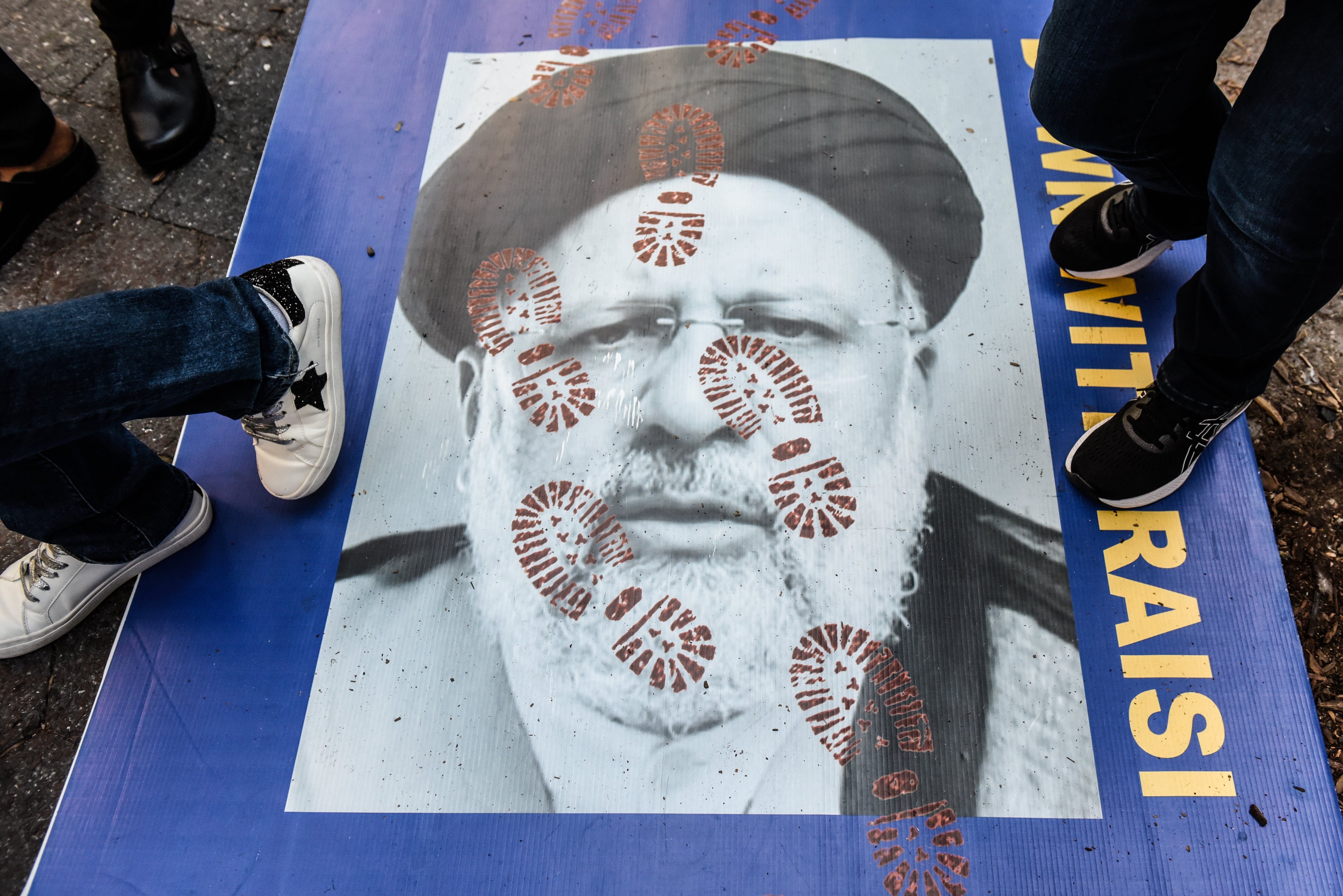 People step on a poster of Iranian president Ebrahim Raisi as they participate in a protest outside the United Nations