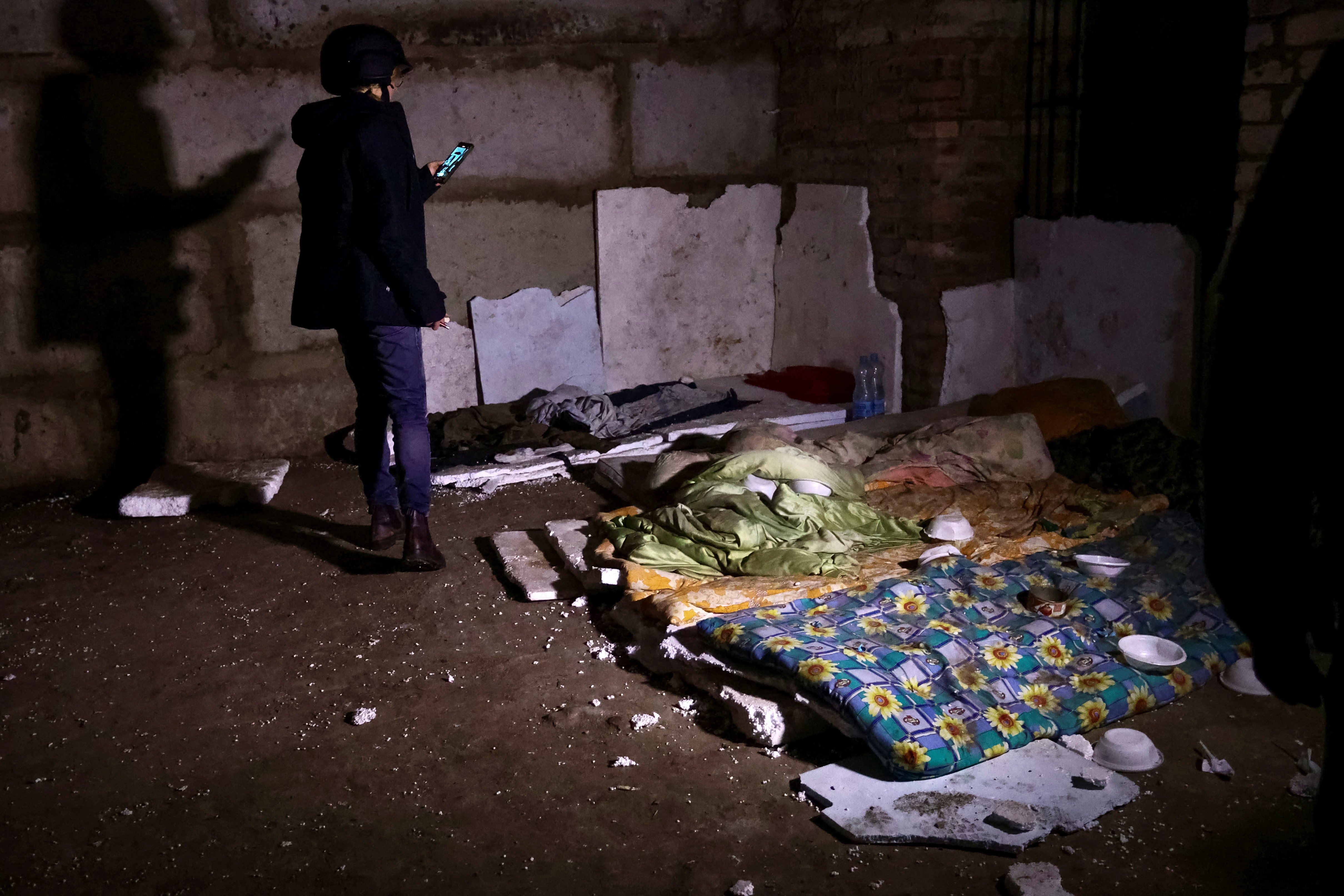 Woman takes a picture inside a basement of a building, which Ukrainian authorities say was a makeshift Russian prison and torture chamber during Russia's invasion in Kozacha Lopan