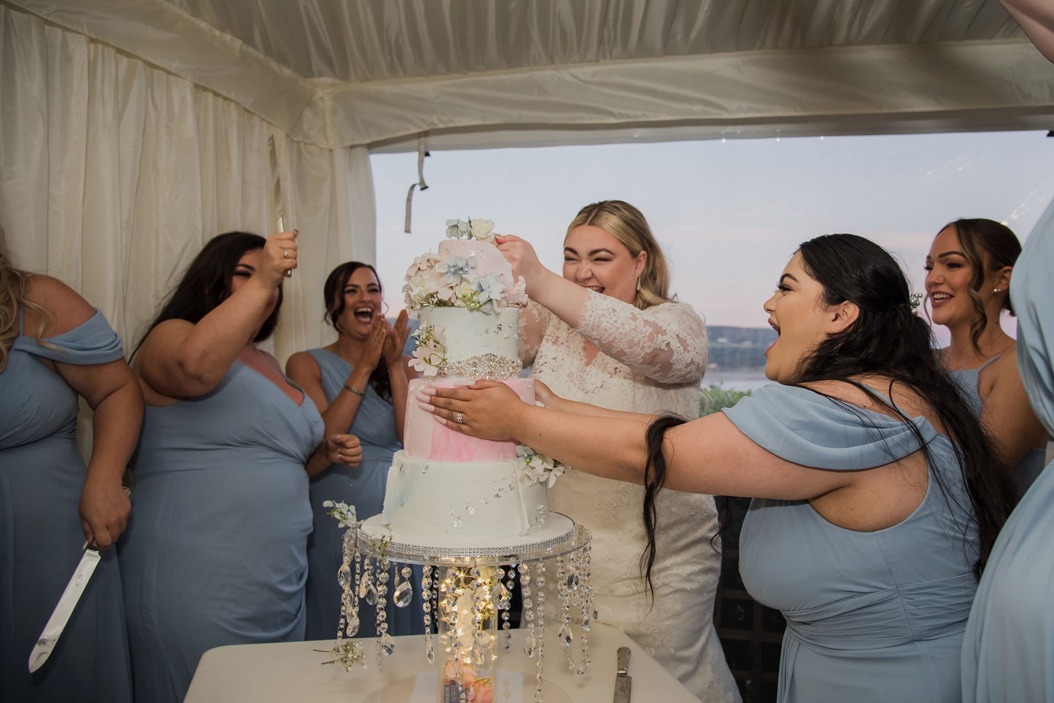 Kayley Stead and her bridesmaids laugh as they cut the wedding cake