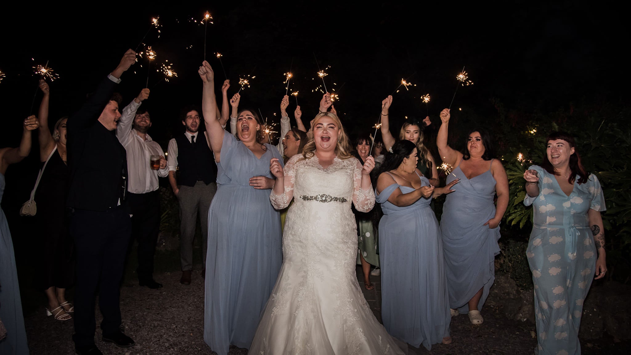 Kayley Stead and her bridesmaids and guests wave sparklers