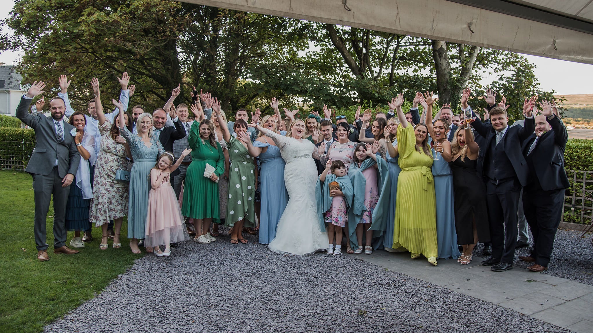 Kayley Stead smiles and waves at the camera alongside her wedding parties