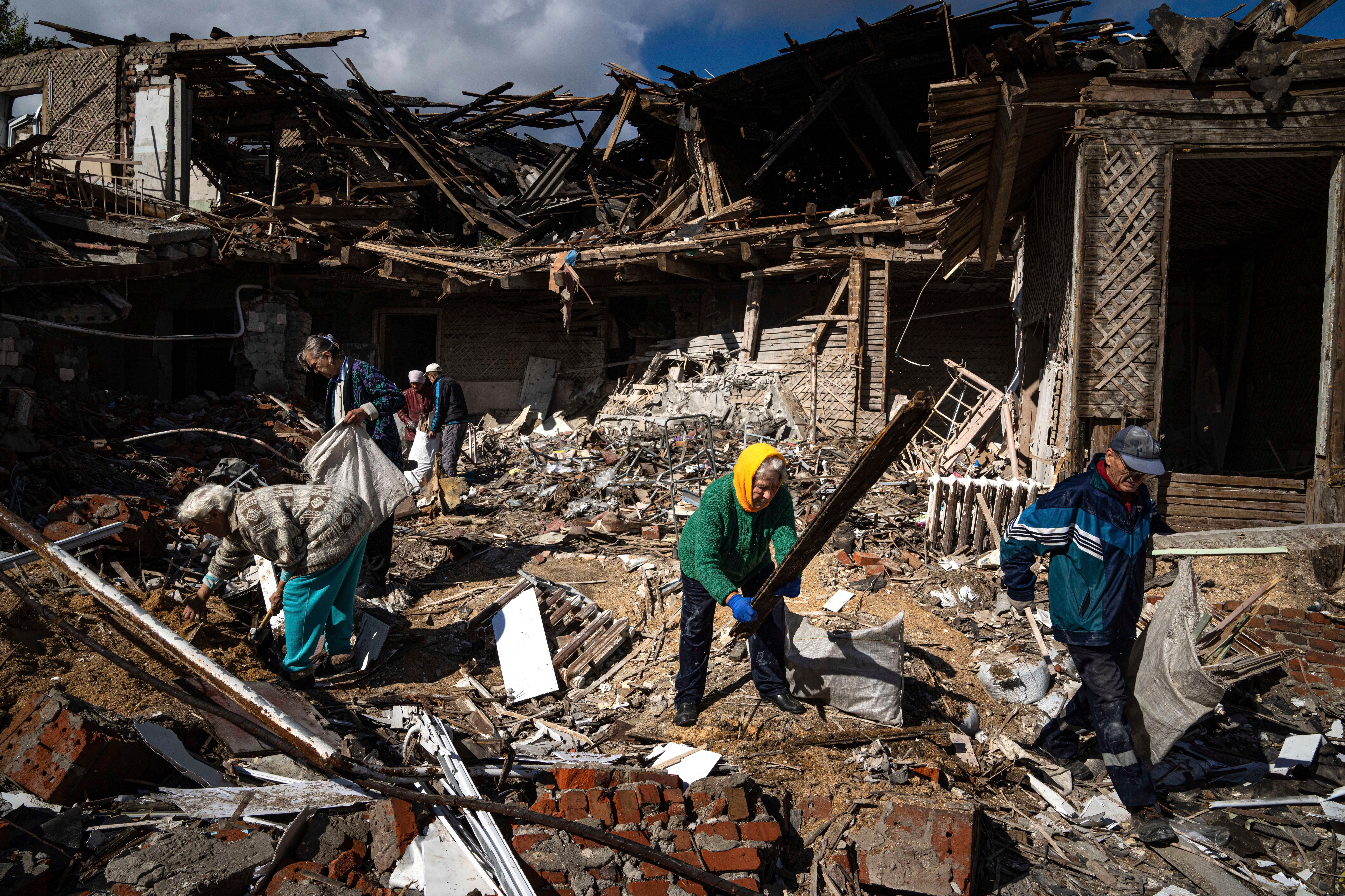 Local residents collect wood for heating from a destroyed school where Russian forces were based, in the recently retaken area of Izium, Ukraine (Evgeniy Maloletka/AP)