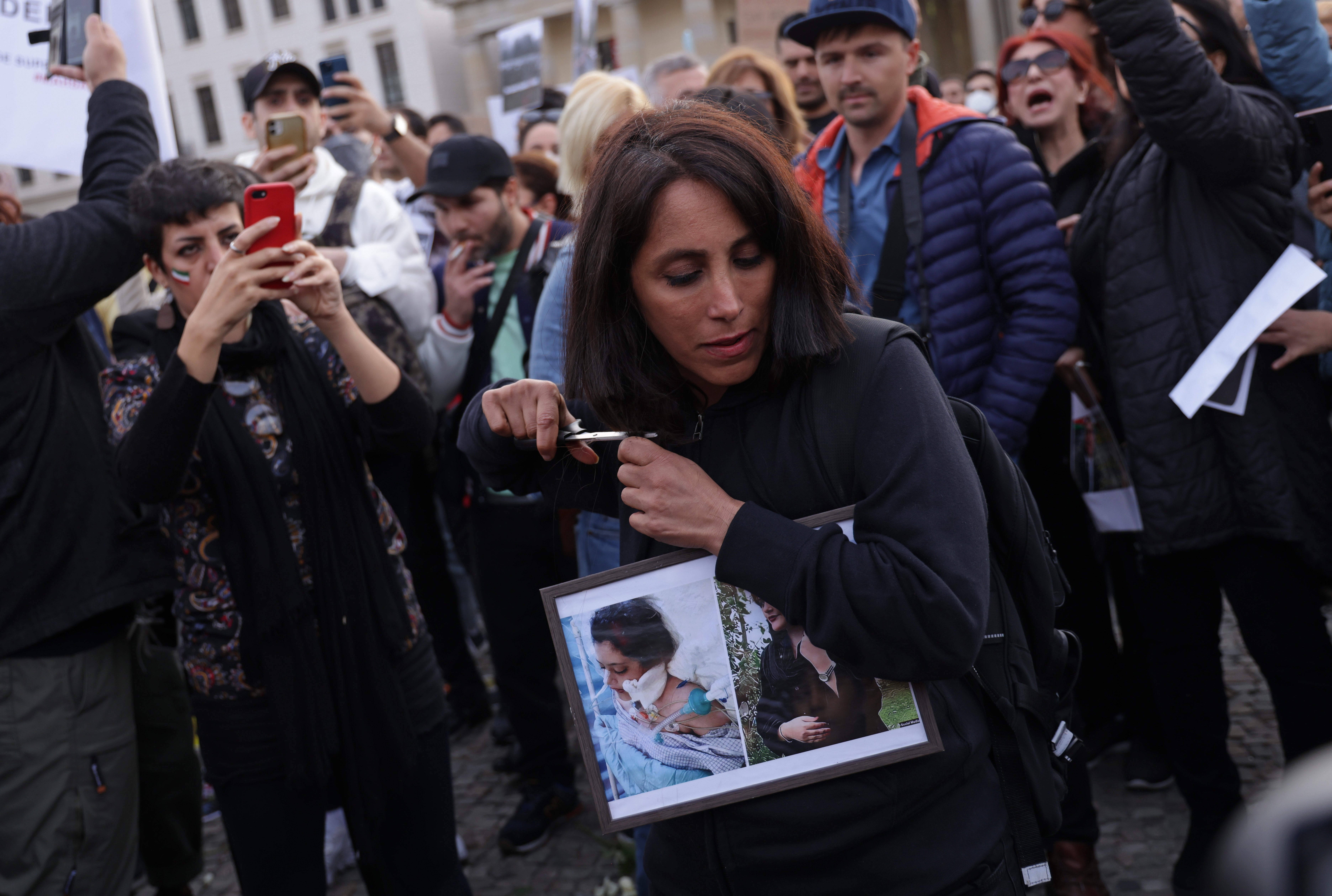 A female protester in Berlin cuts her hair with scissors as an act of solidarity with women in Iran