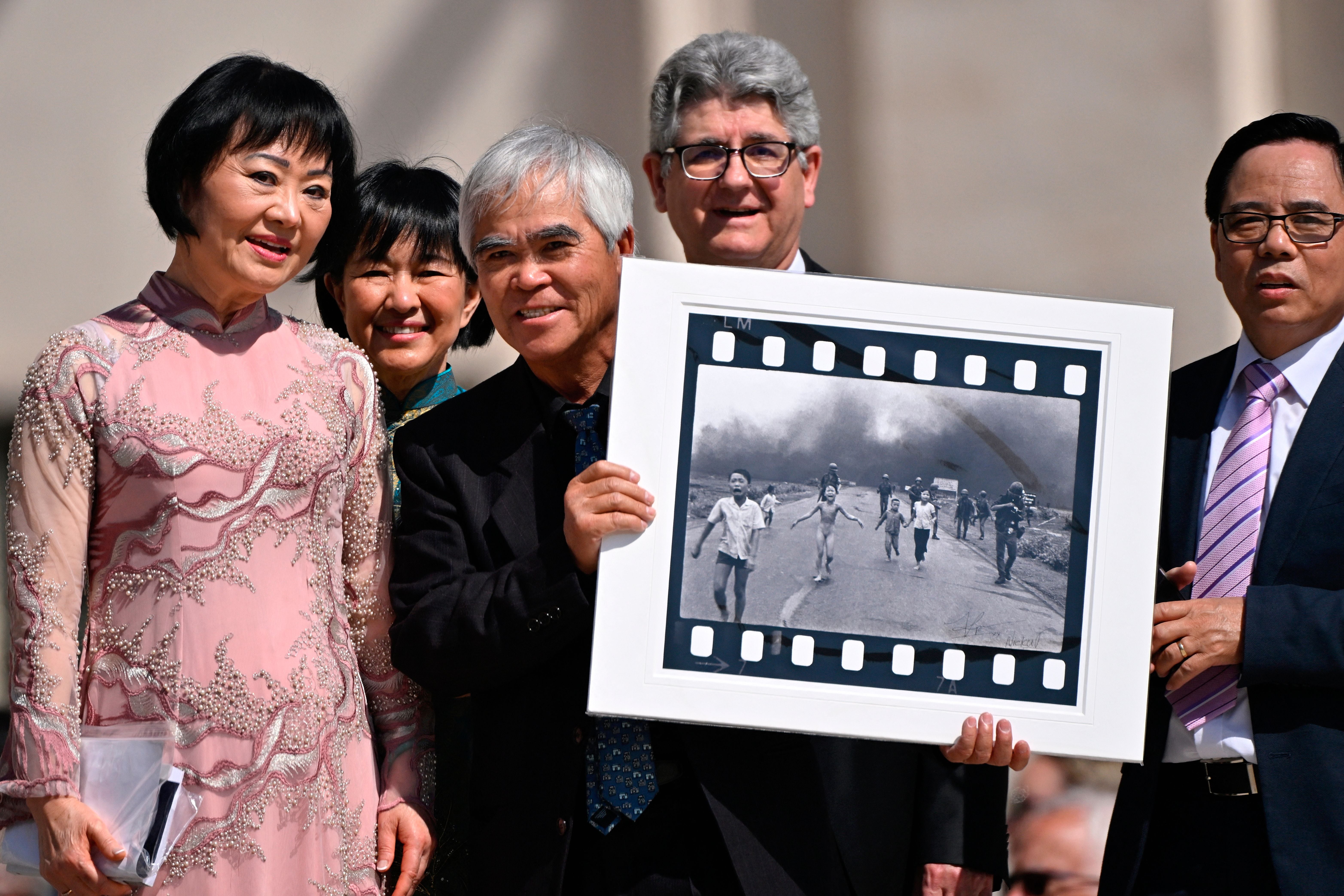 Ut holds his photo in Vatican City alongside Kim Phuc, the girl in the image