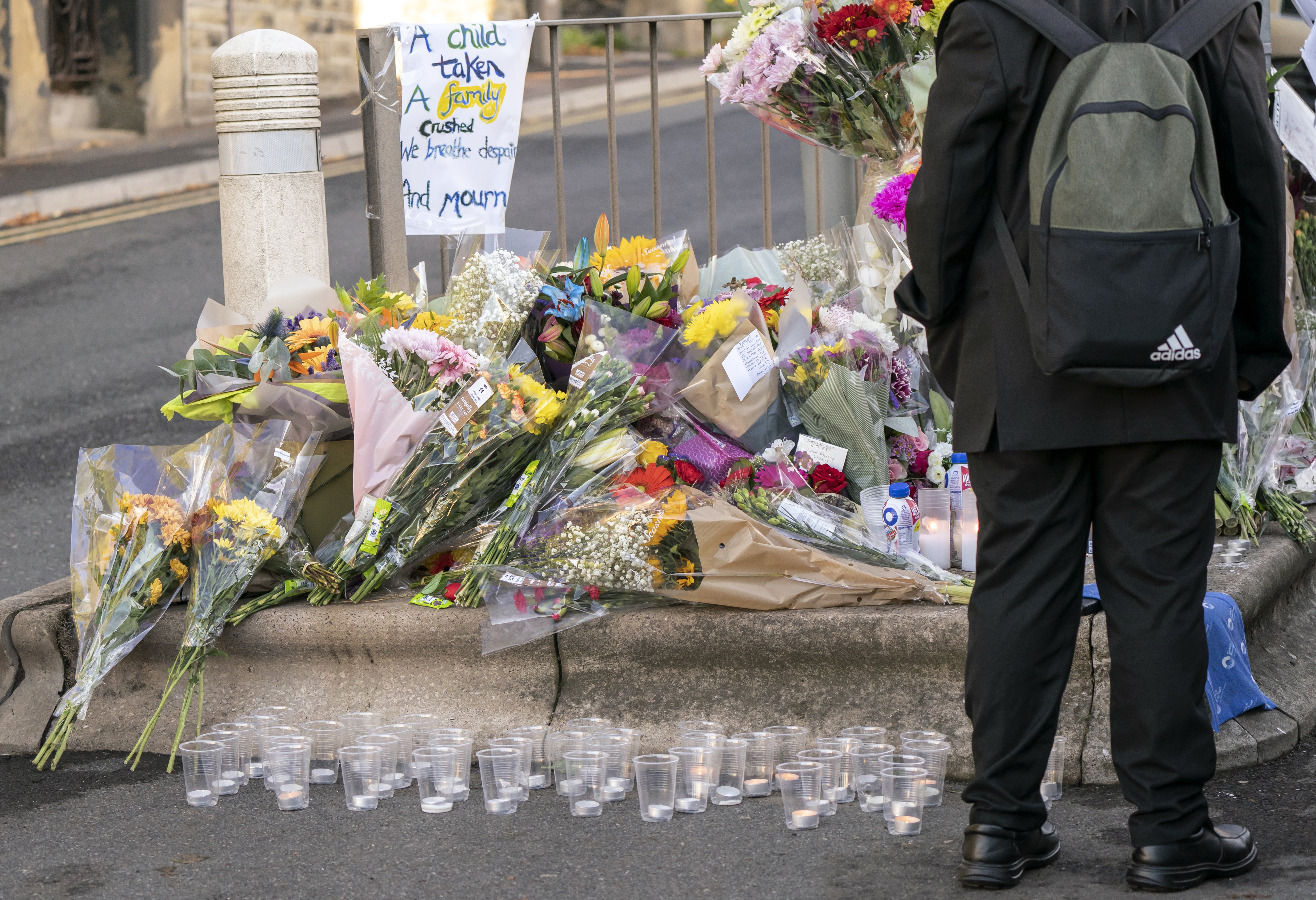 A pupil looks at floral tributes at the scene in Woodhouse Hill, Huddersfield, where 15-year-old schoolboy Khayri McLean was fatally stabbed outside his school gates (Danny Lawson/PA)