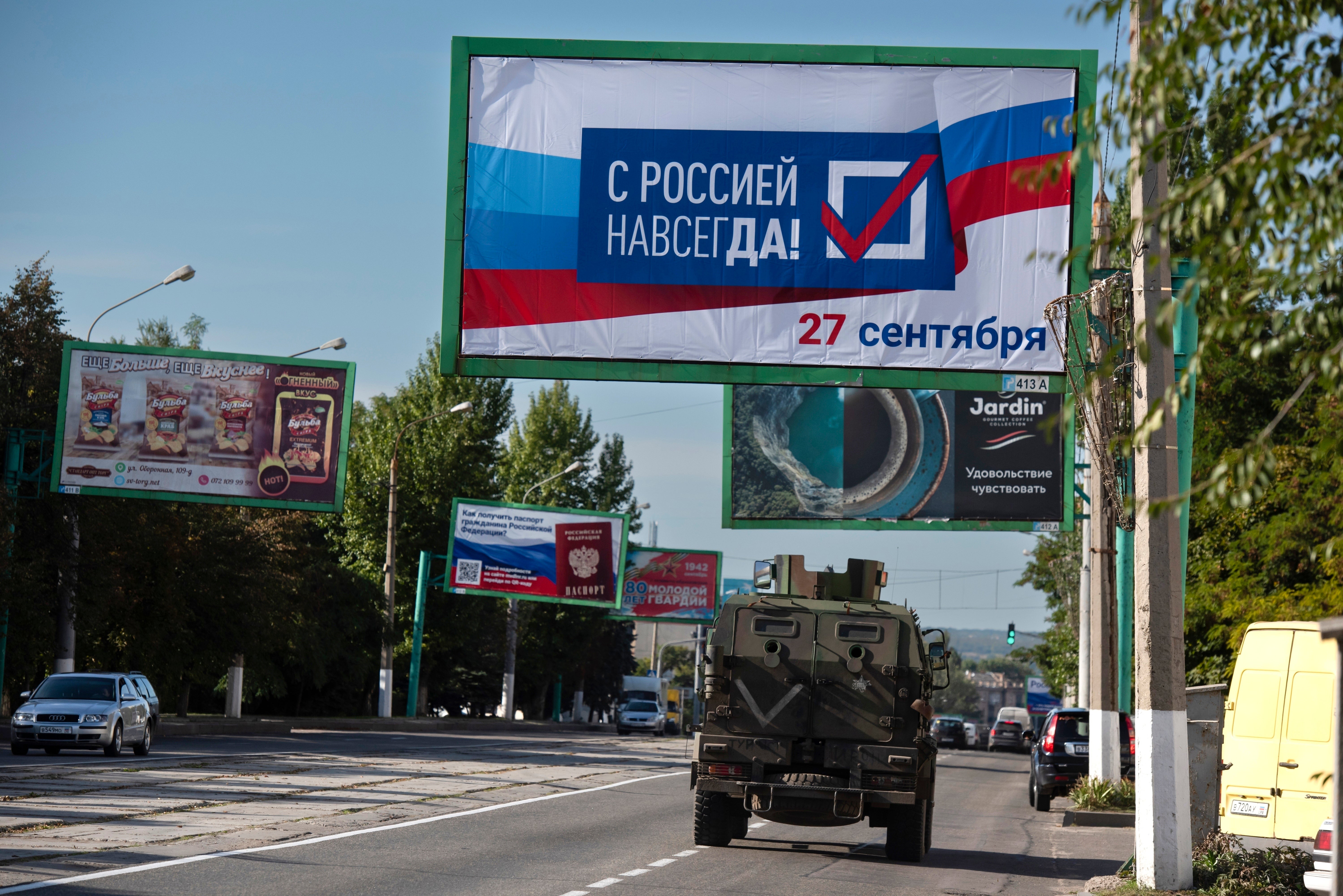 A military vehicle drives along a street with a billboard that reads: ‘With Russia forever, 27 September’, prior to a referendum in Luhansk, Luhansk People’s Republic