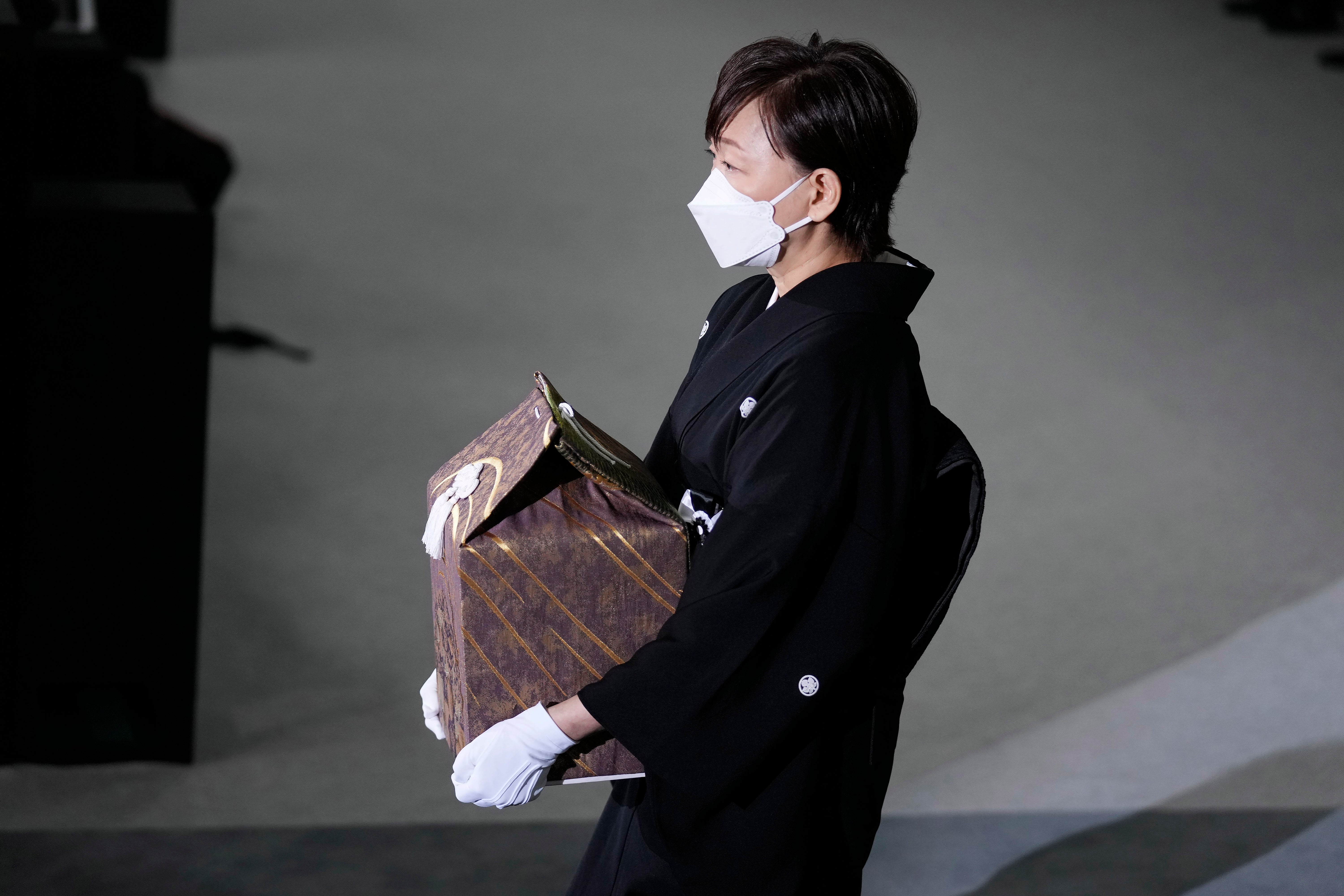 Akie Abe, wife of former Prime Minister Shinzo Abe, carries a cinerary urn containing his ashes at his state funeral, Tuesday, Sept. 27, 2022, in Tokyo