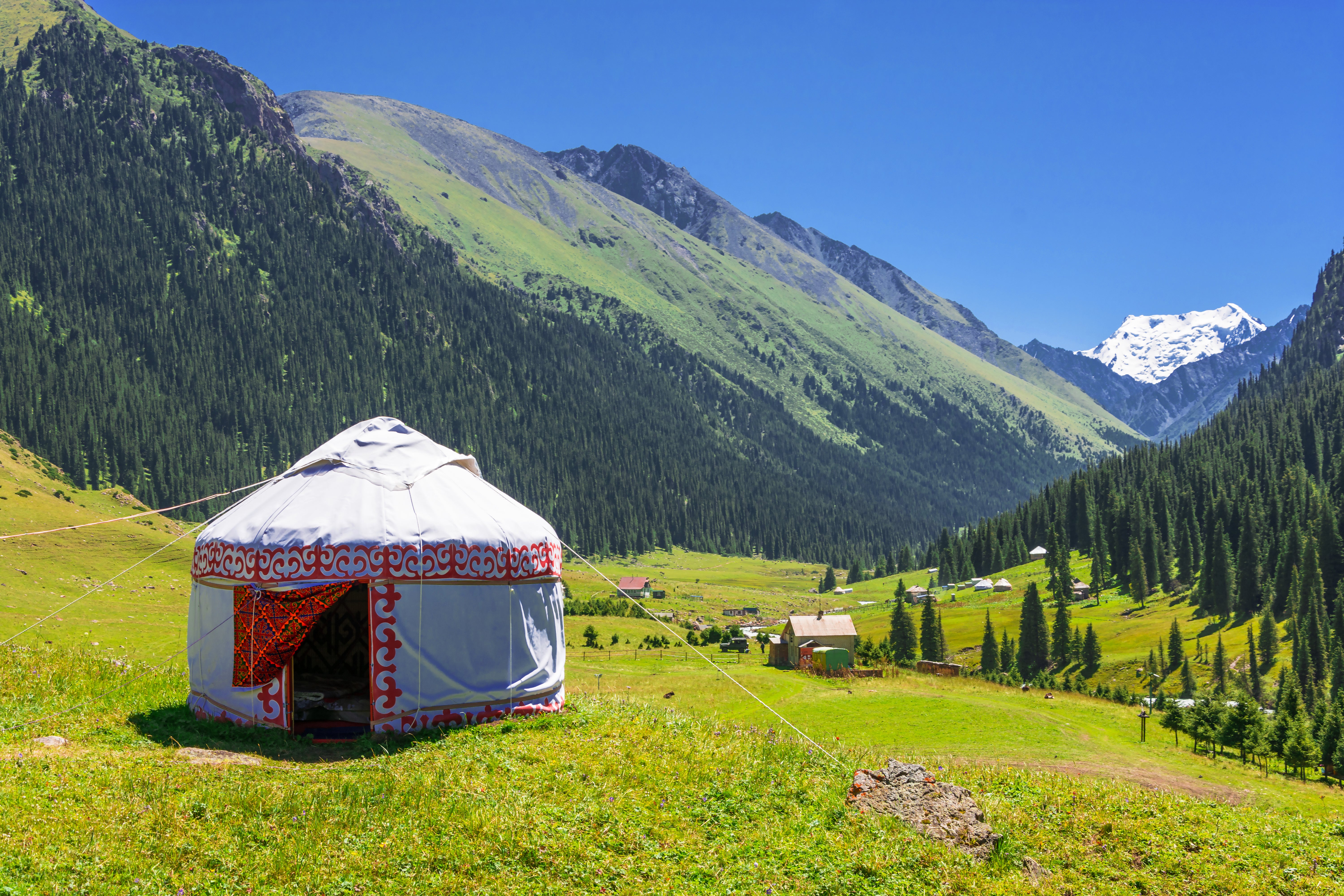 Kyrgyzstan mountain landscape with a white Yurt, decorated with a red ornament