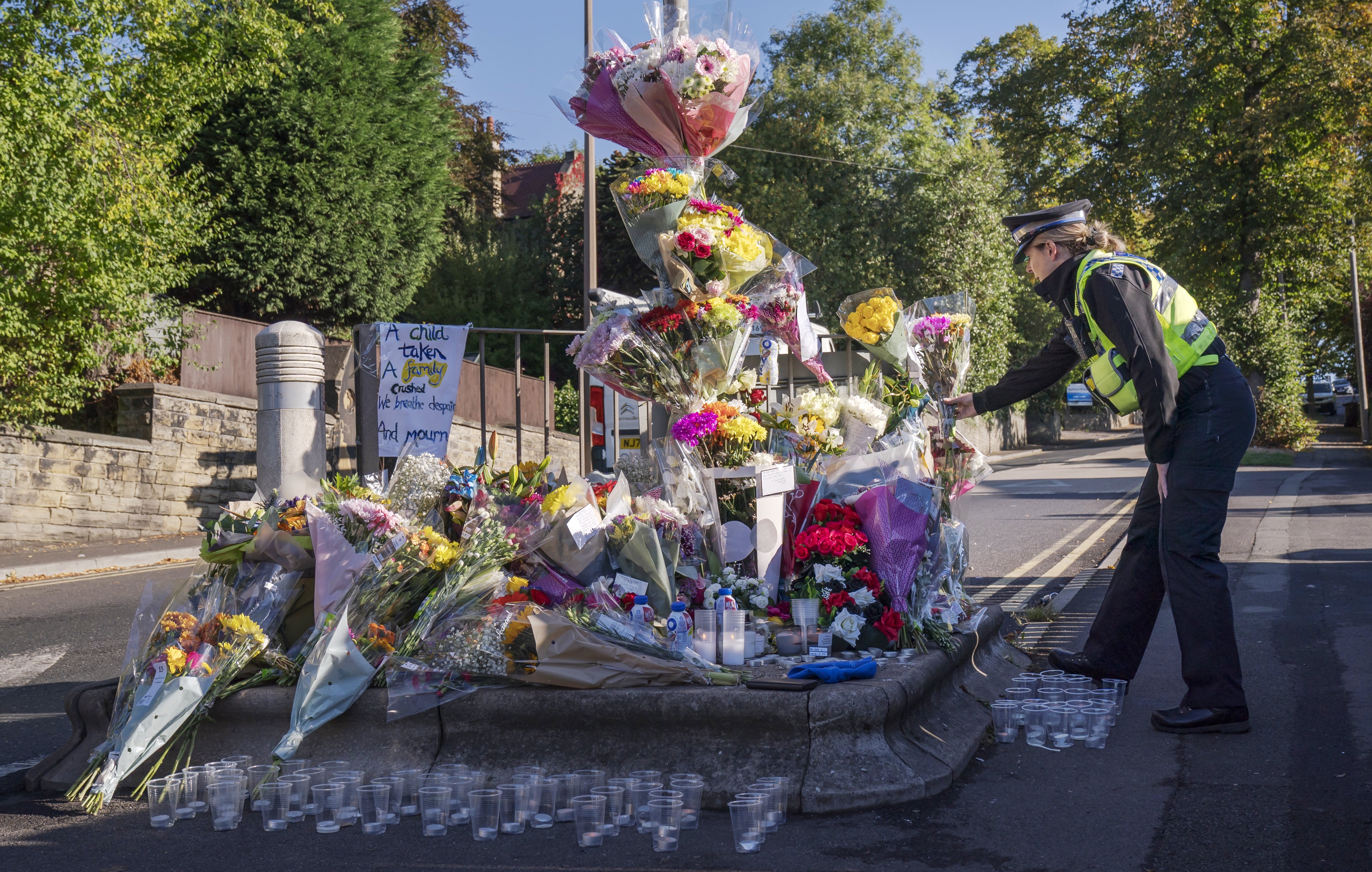 A police community support officer lays a floral tribute at the scene in Woodhouse Hill (Danny Lawson/PA)