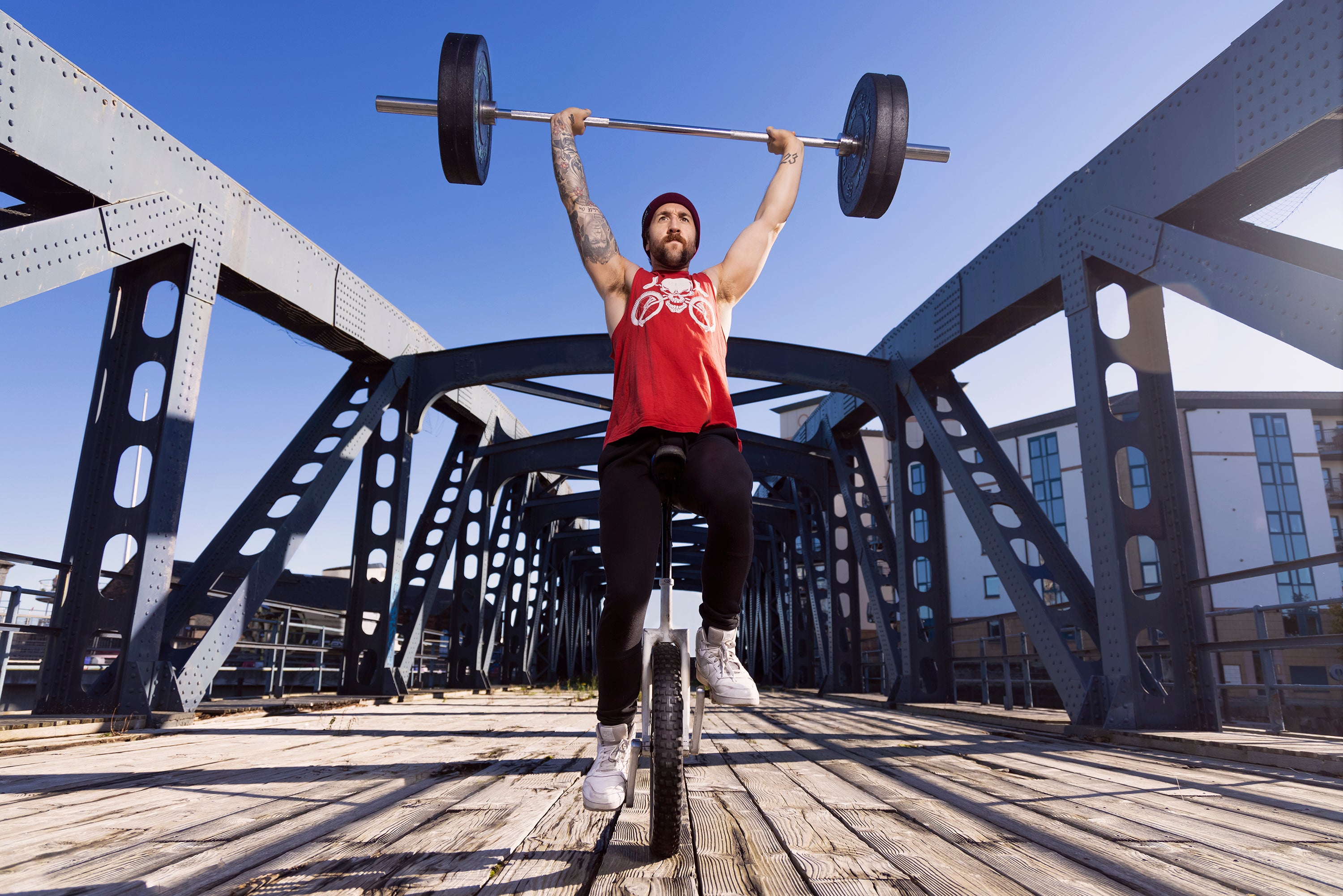 Jason Auld riding a unicycle and holding a weight above his head (Guinness World Records/Rod Penn/PA)