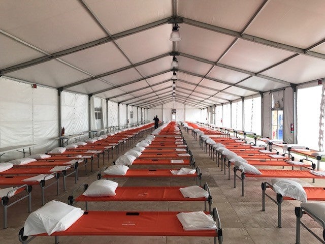 A model of a shelter in The Bronx for newly arrived migrants shows rows of cots under a large tent-like facility.