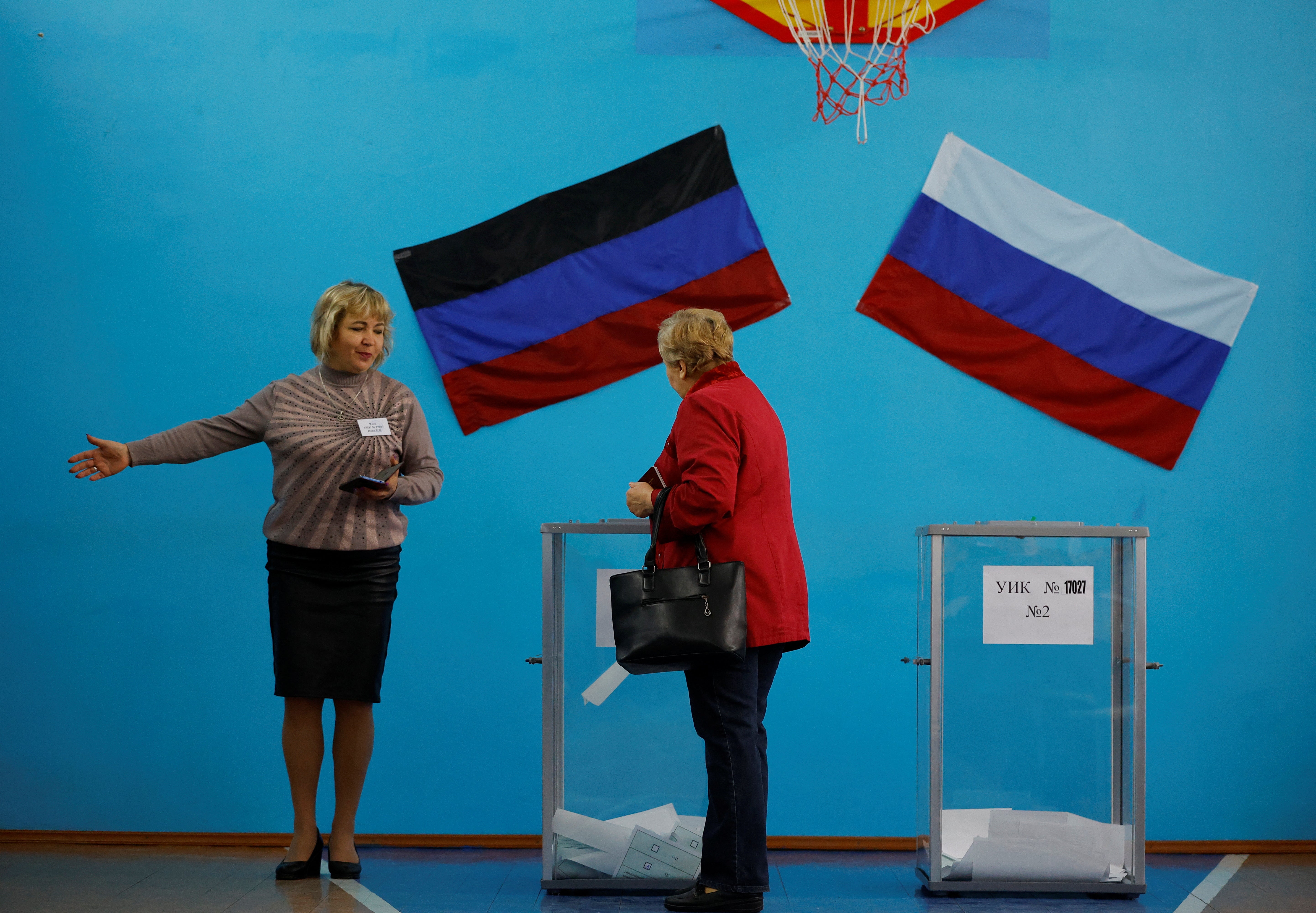 A member of an electoral commission shows the way to a voter at a polling station in Donetsk