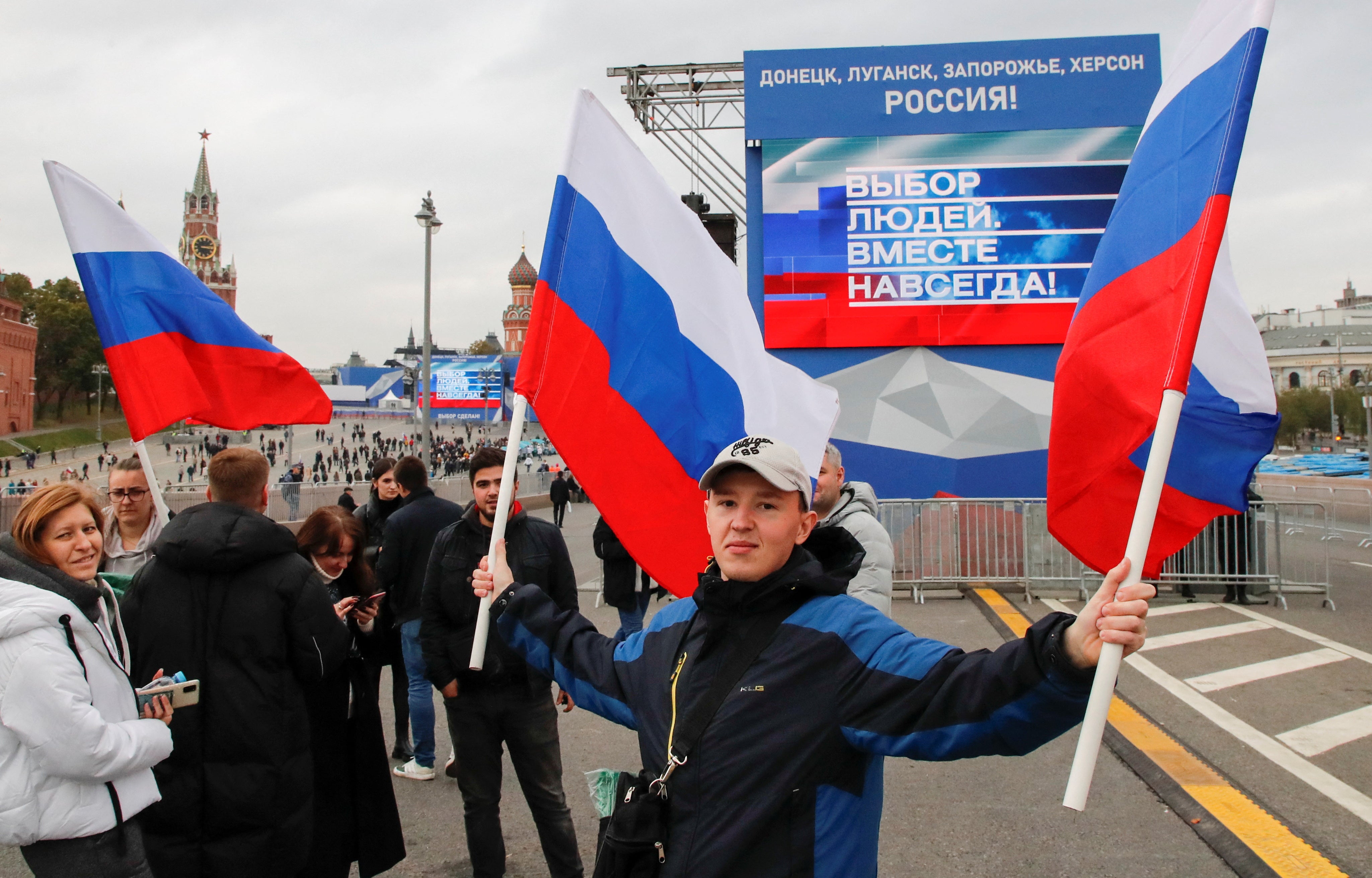 People gather in front of screens located near the Kremlin and Red Square before Mr Putin’s speech