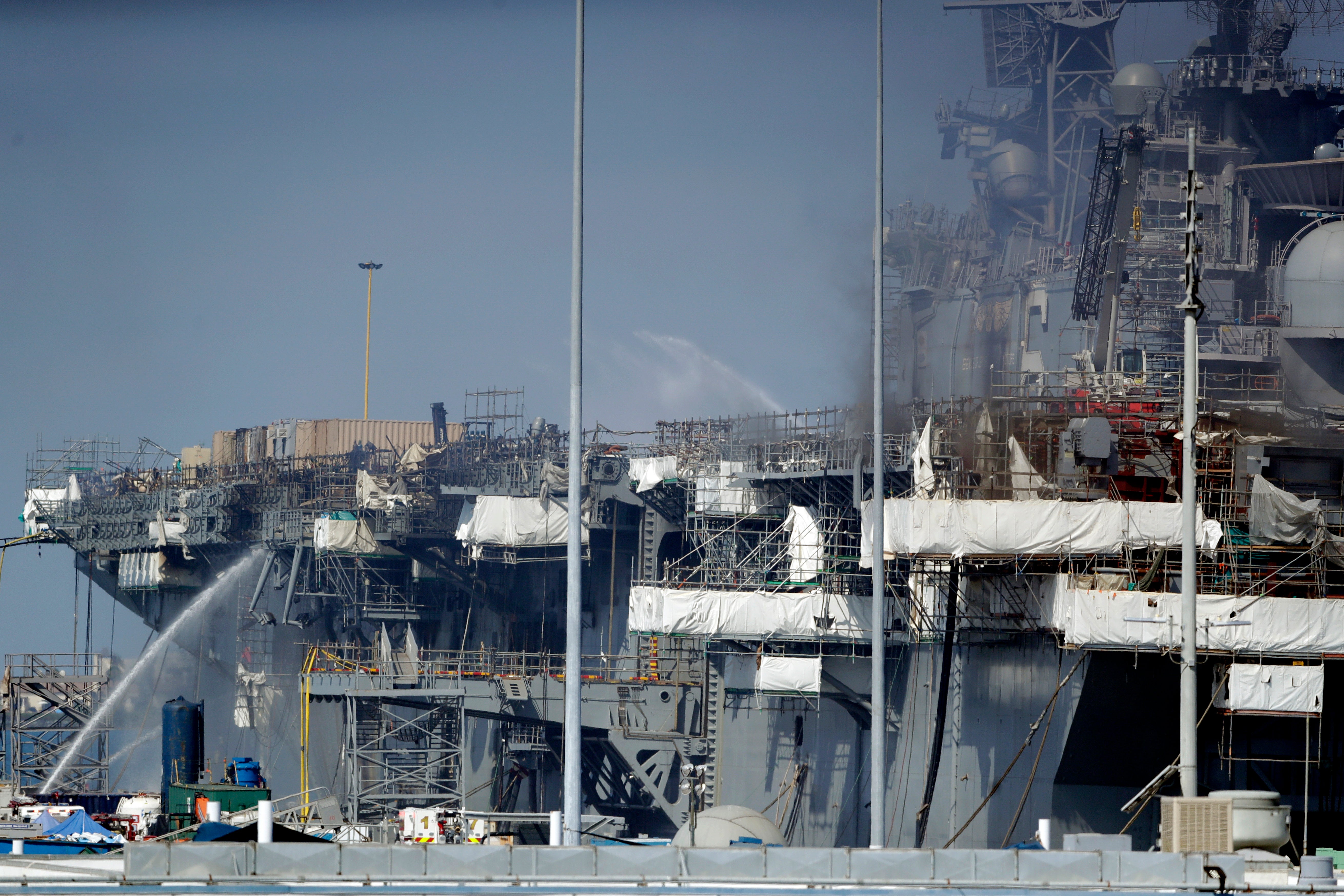FILE - Fire crews spray water from the dock onto the side of the USS Bonhomme Richard, in San Diego, July 12, 2020