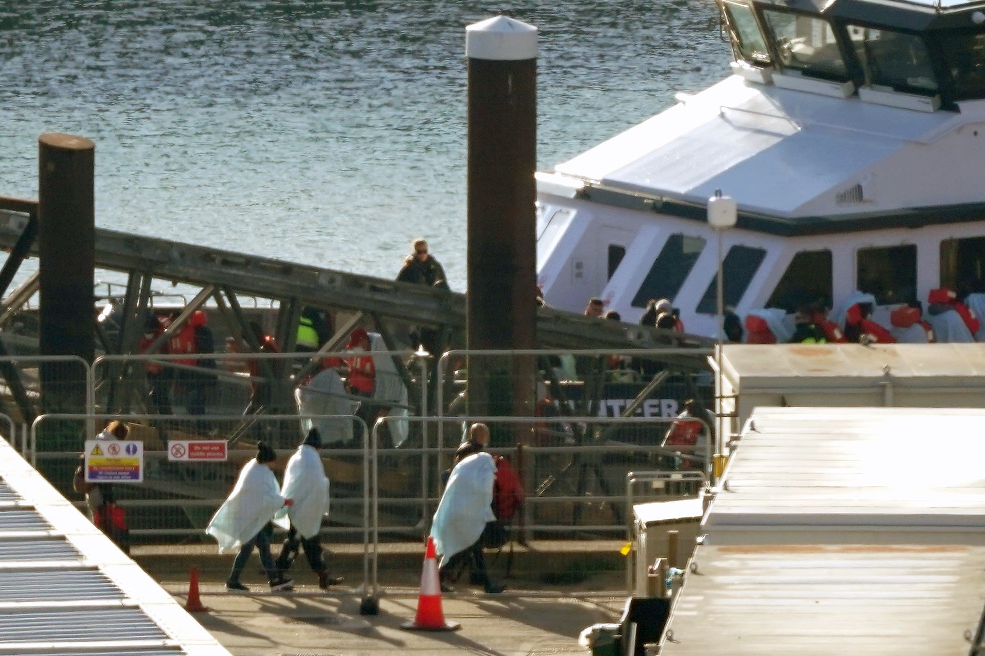 People thought to be migrants walk through the Border Force compound in Dover, Kent, after being brought from a Border Force vessel following a small boat incident in the Channel. Picture date: Thursday September 29, 2022.(Gareth Fuller/PA)