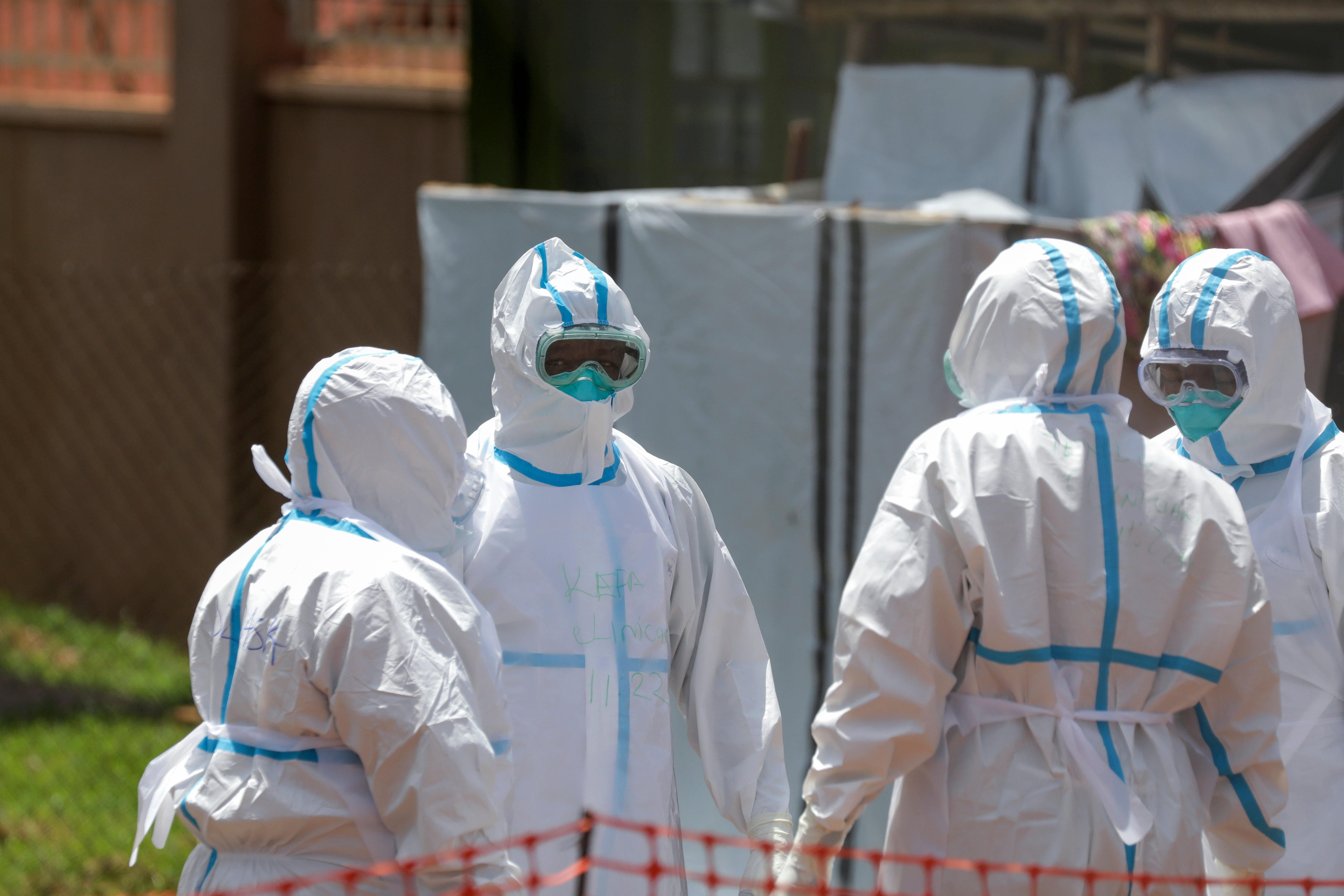 Doctors stand in a circle to say a prayer before entering the Ebola isolation section of Mubende Regional Referral Hospital