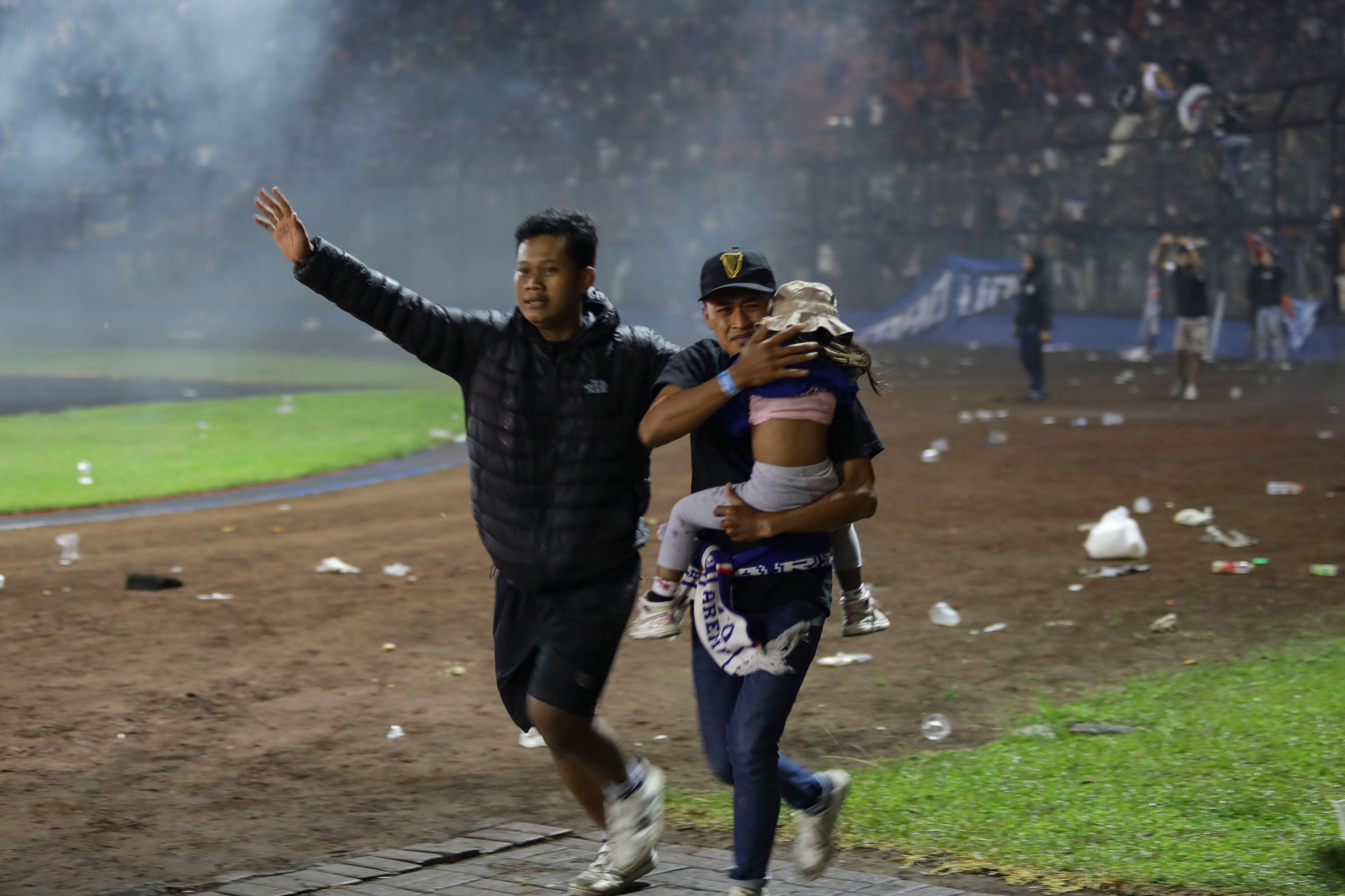 Football fans evacuate a girl during a clash between fans at Kanjuruhan Stadium