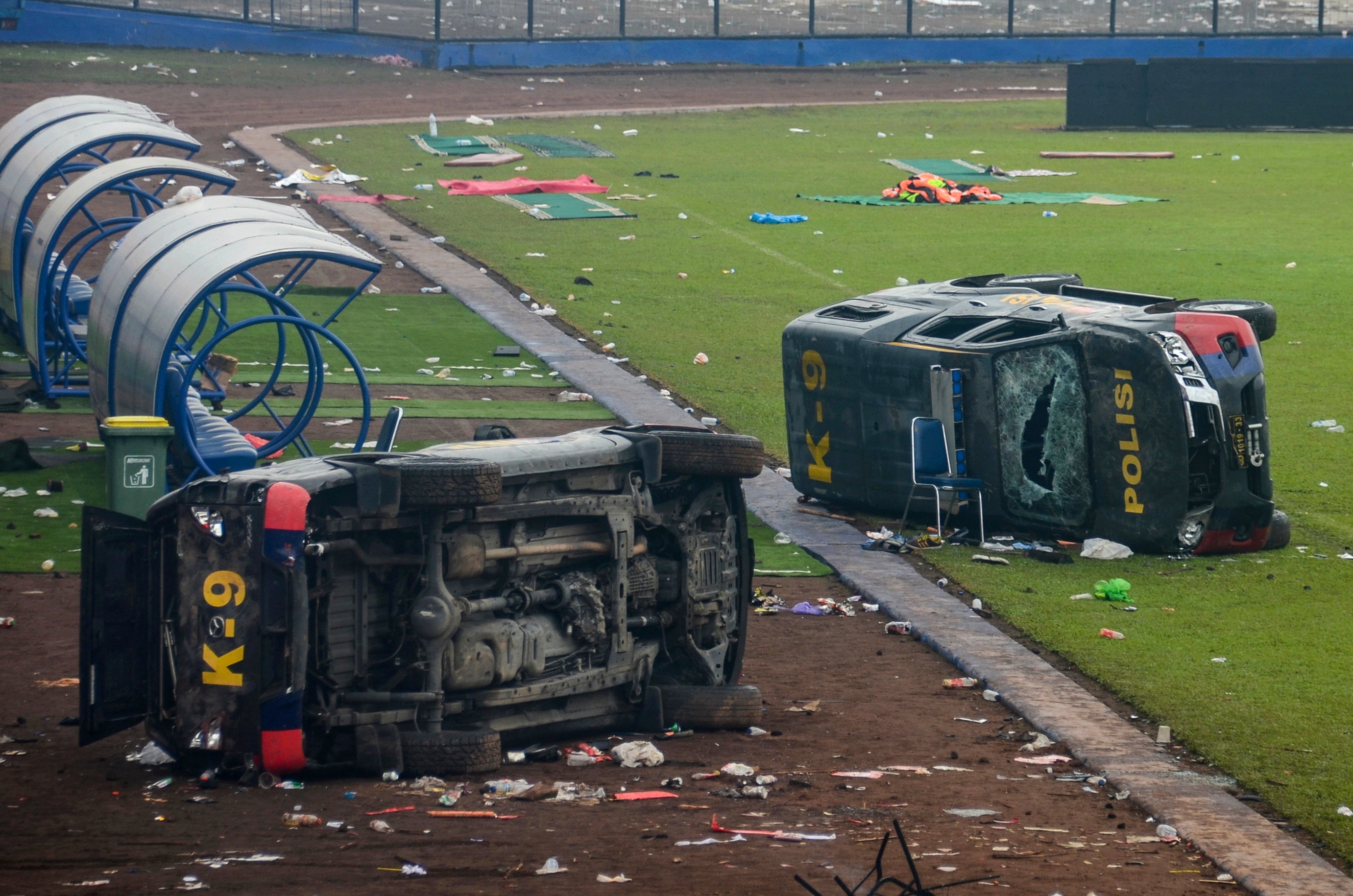 Damaged police vehicles lay on the pitch