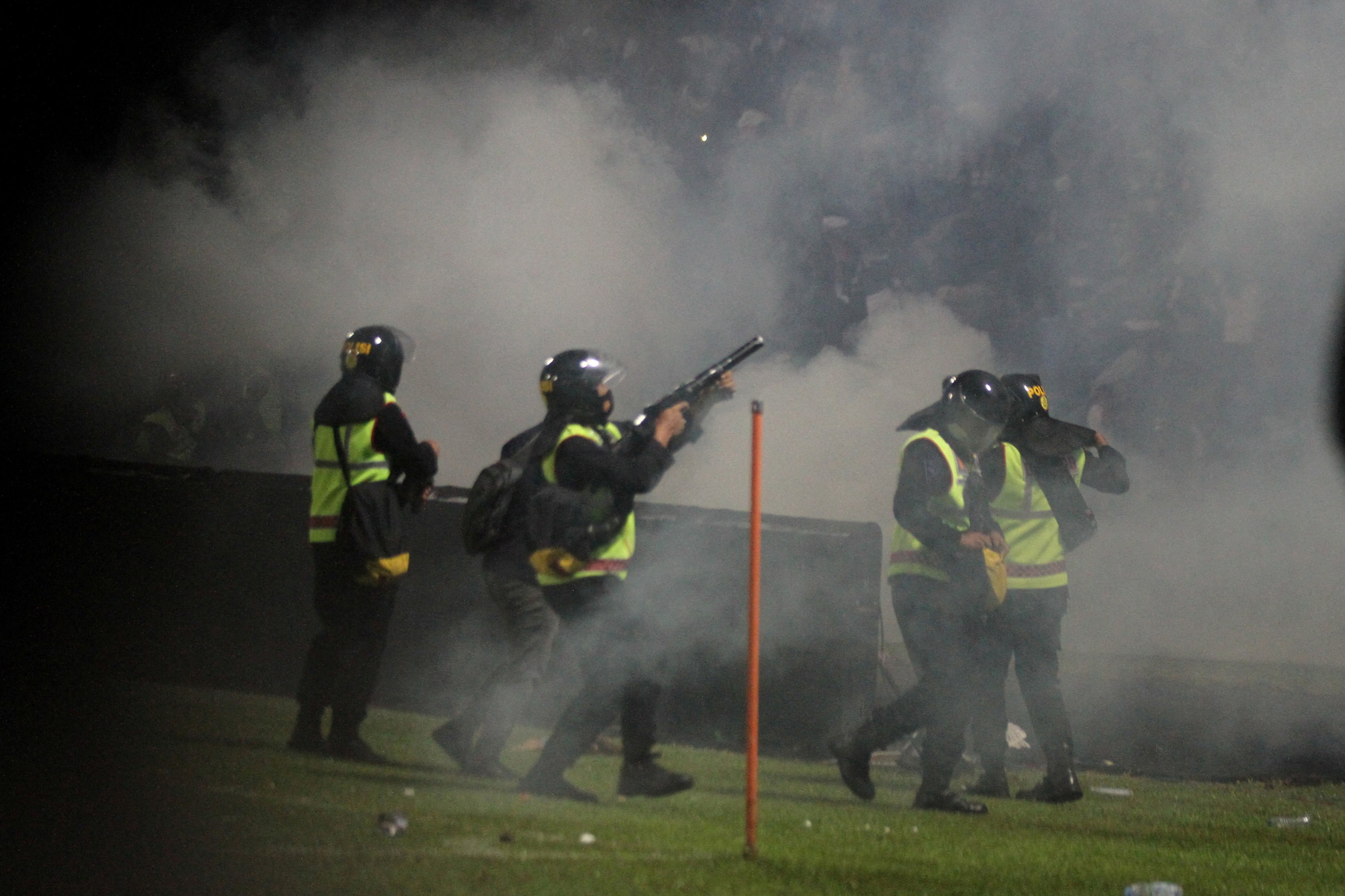 A police officer fires tear gas during the riot