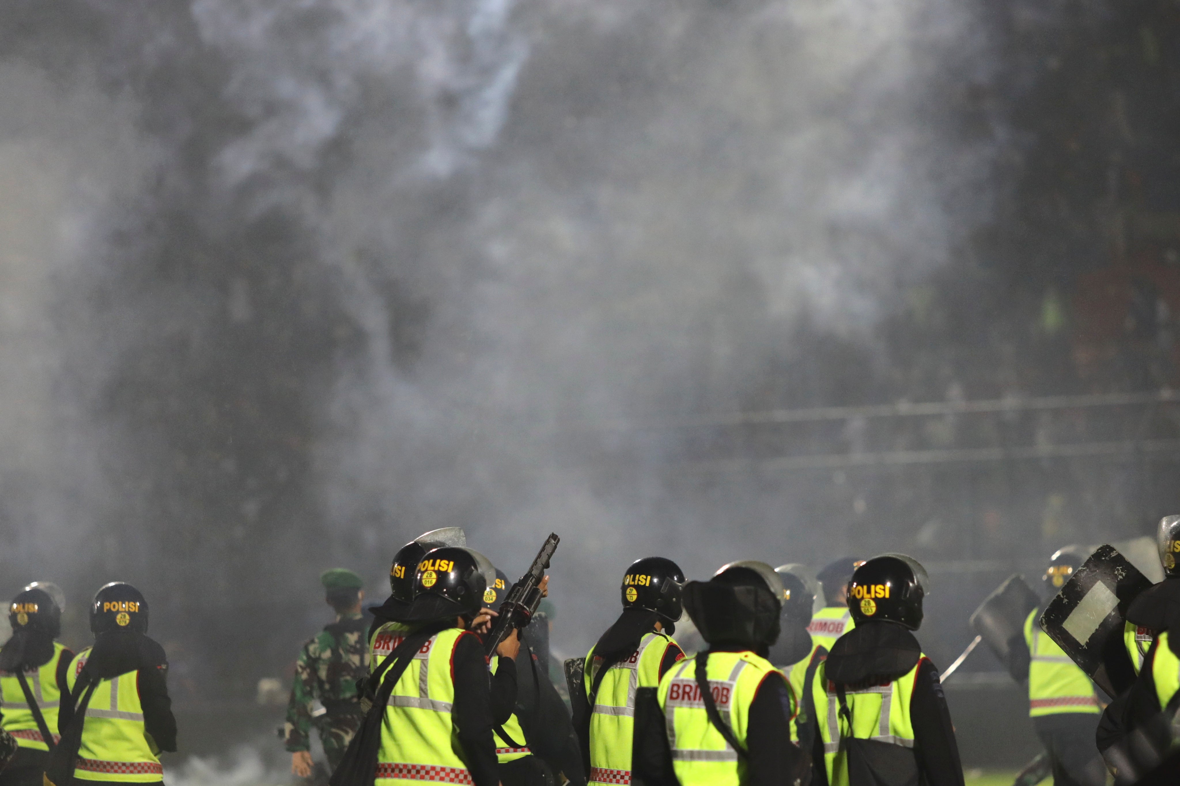 Police officers fire tear gas during a riot following a football match at Kanjuruhan stadium in Malang